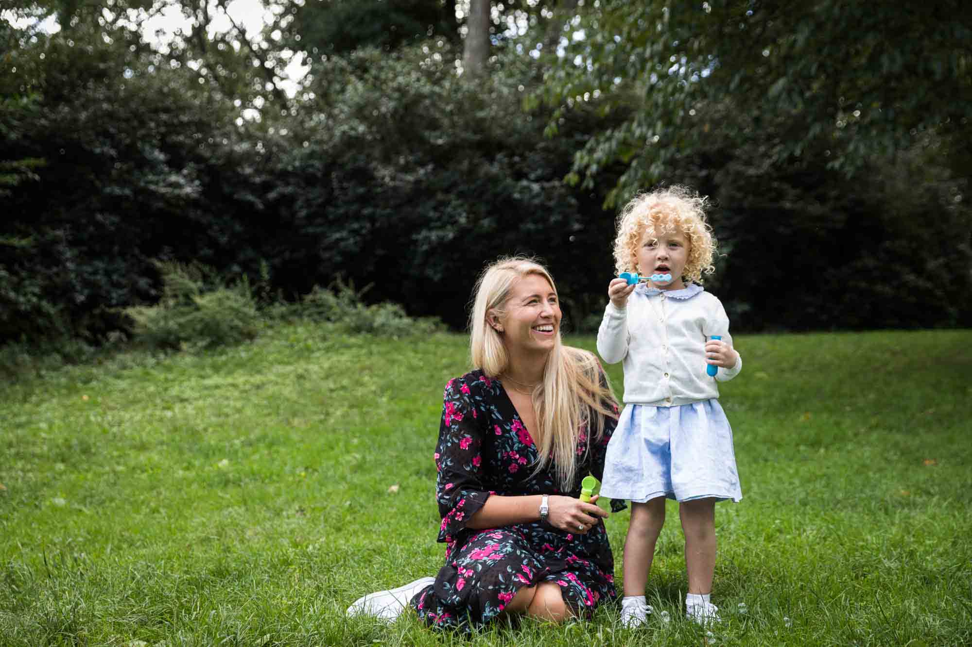 Central Park family portrait of mother and little girl sitting in grass