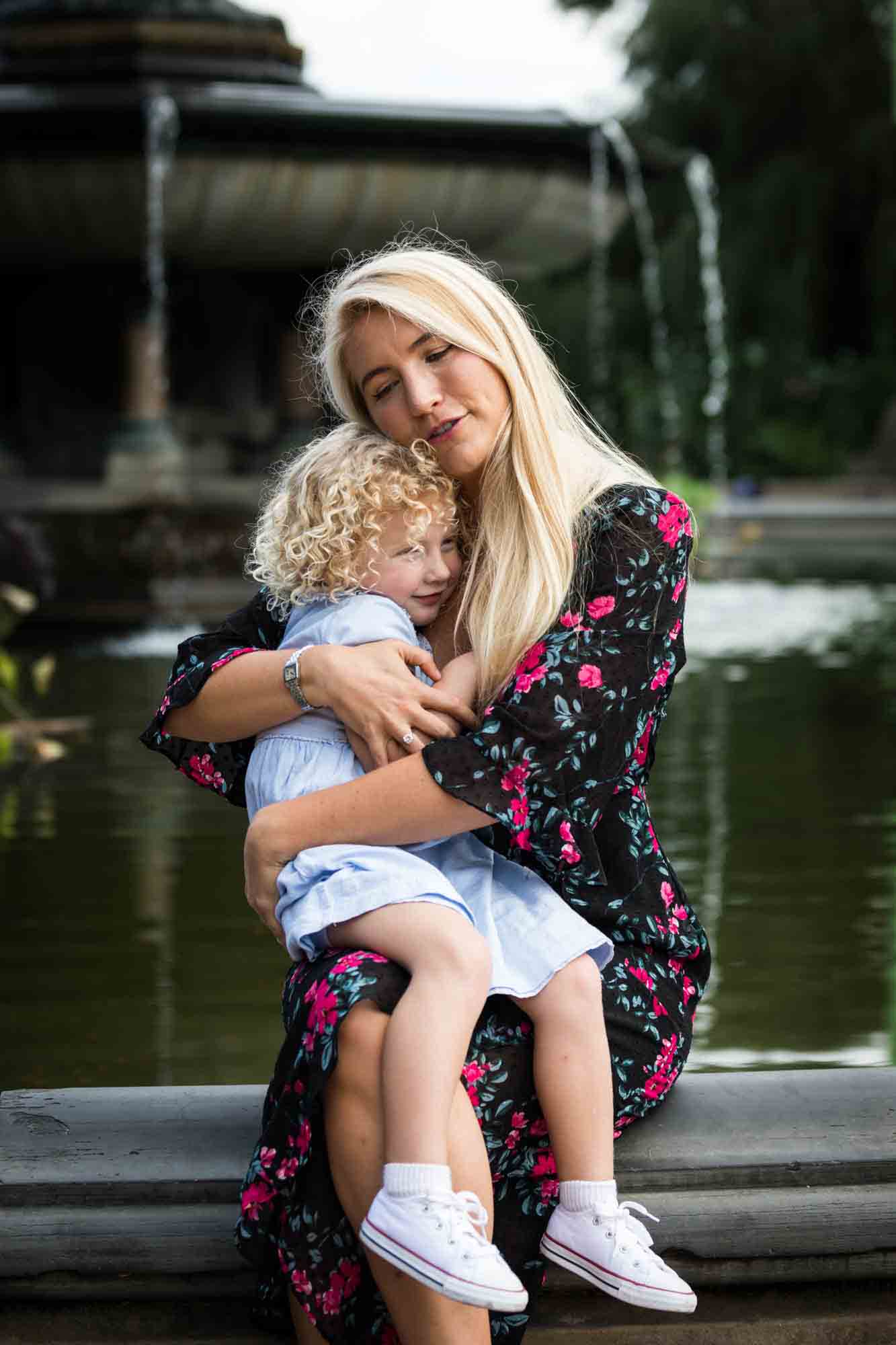 Blonde mother holding little blonde girl in front of Bethesda Fountain for an article on NYC family portrait tips for tourists