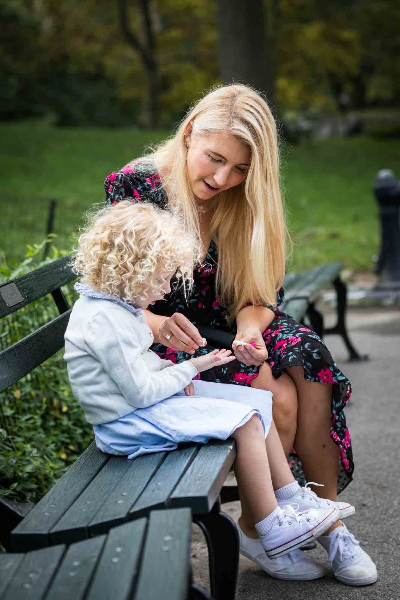 Central Park family portrait of mother and child on bench playing with flower