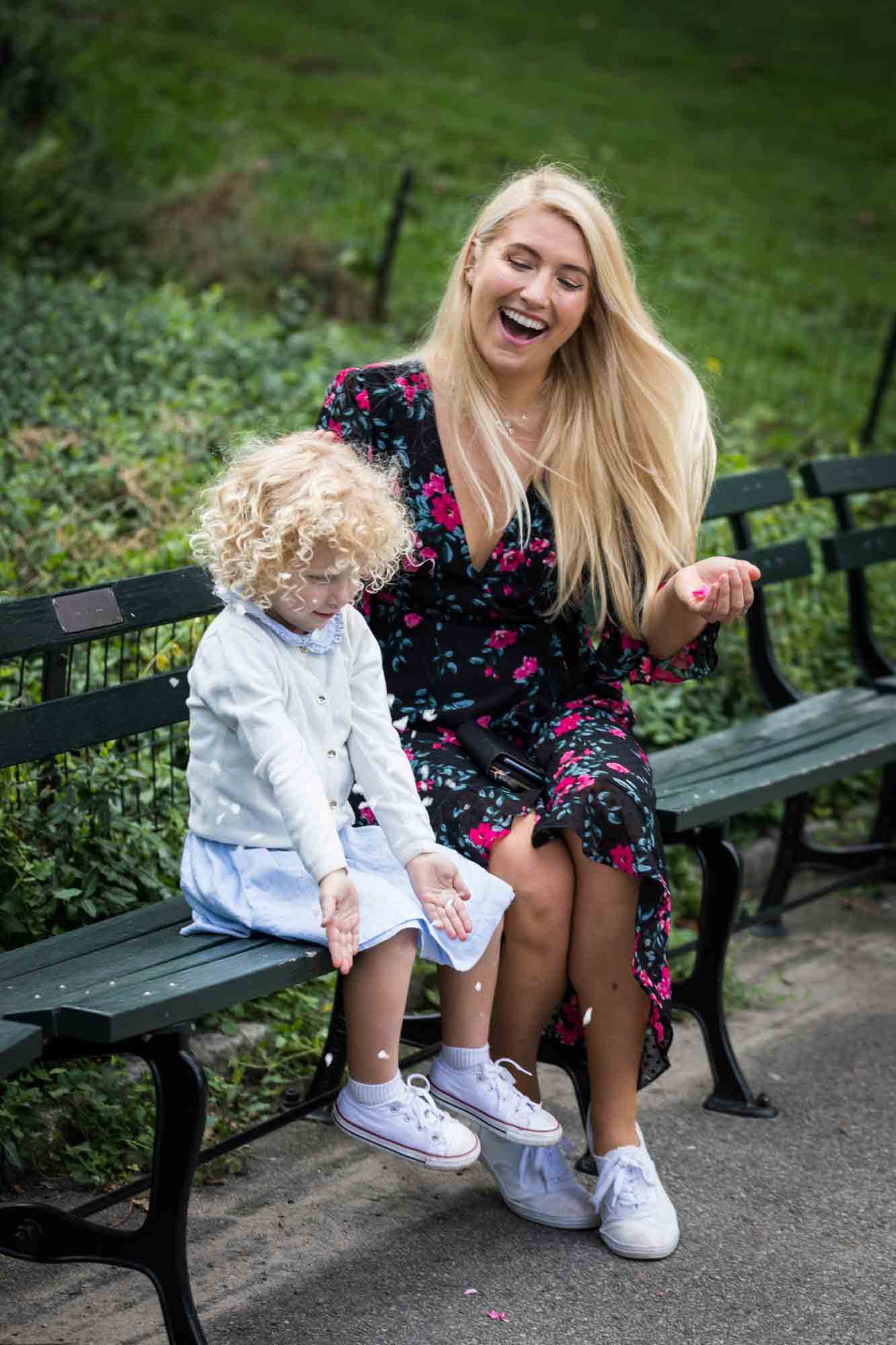 Central Park family portrait of mother and child on bench throwing petals in the air