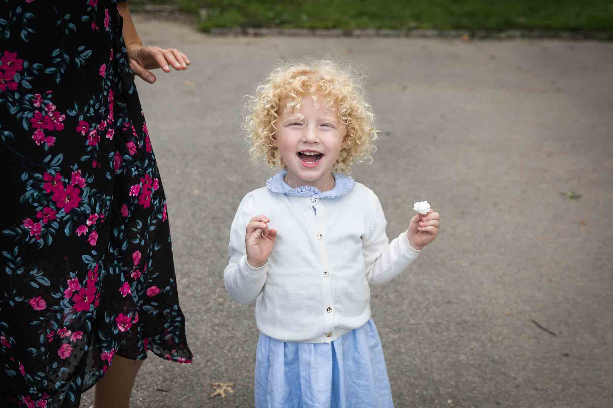 Central Park family portrait of little blonde girl wearing blue dress and white sweater