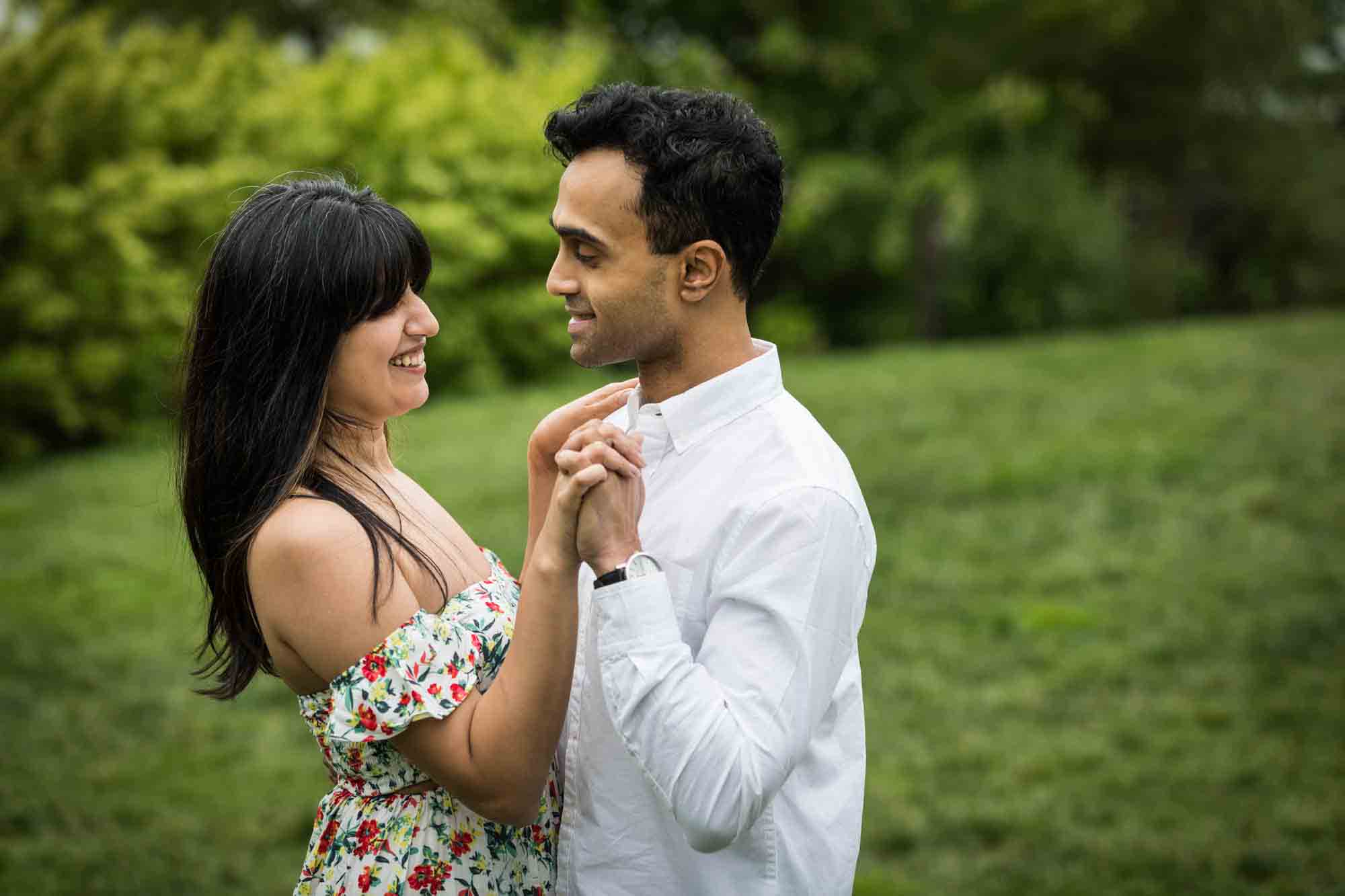 Couple dancing in grass during a Brooklyn Bridge Park engagement photo shoot