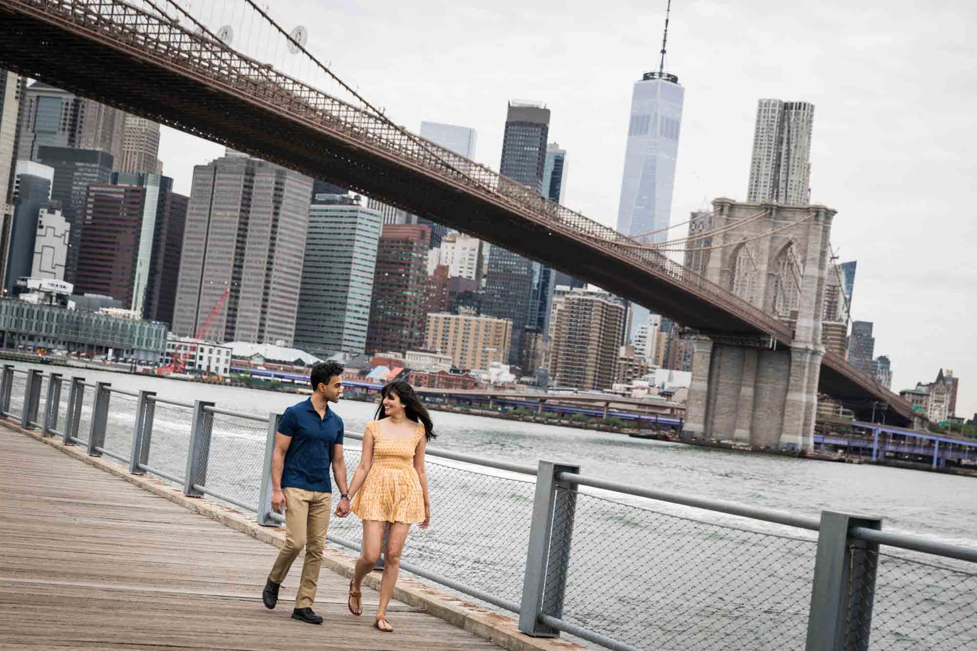 Couple holding hands and walking on boardwalk at Brooklyn Bridge Park