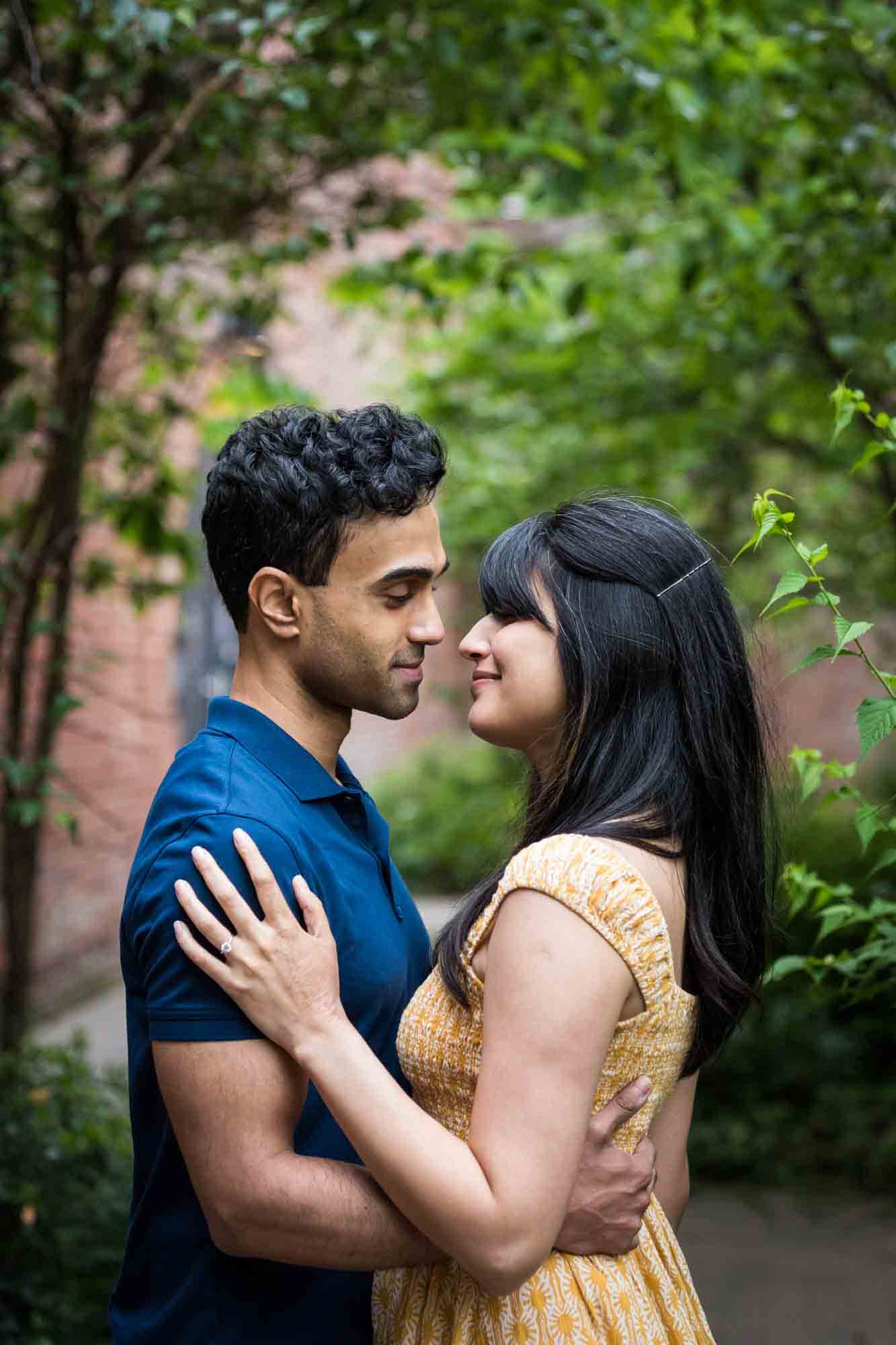 Couple looking at each other in walled garden during a Brooklyn Bridge Park engagement photo shoot