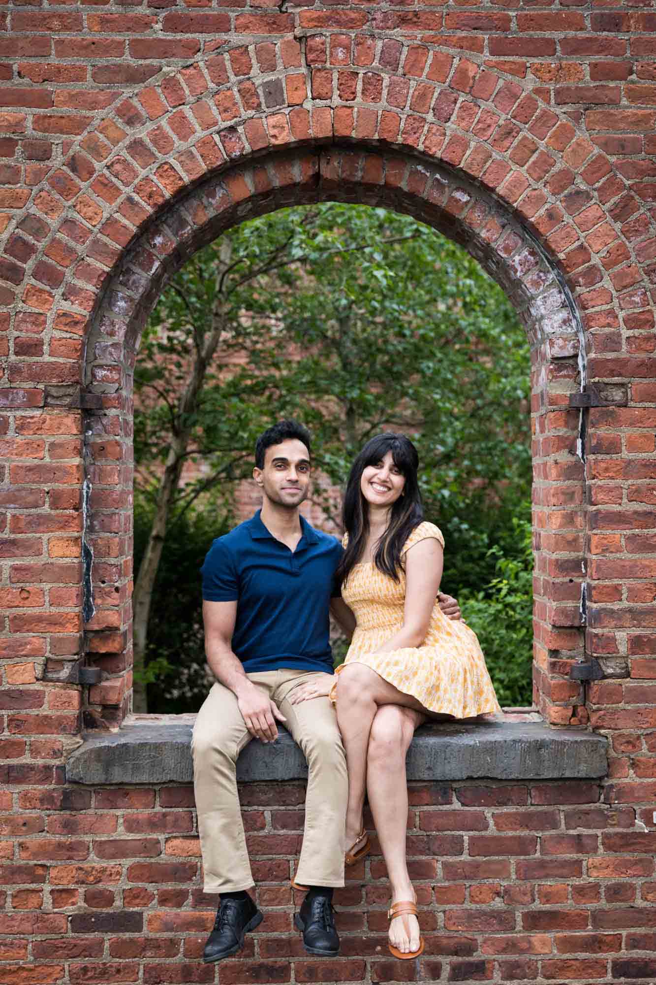 Brooklyn Bridge Park engagement photo of couple sitting in brick window