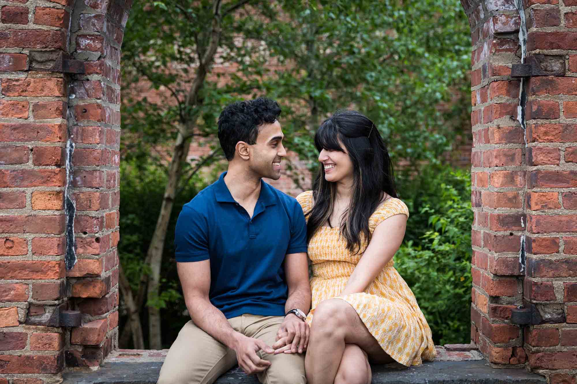 Brooklyn Bridge Park engagement photo of couple sitting in brick window