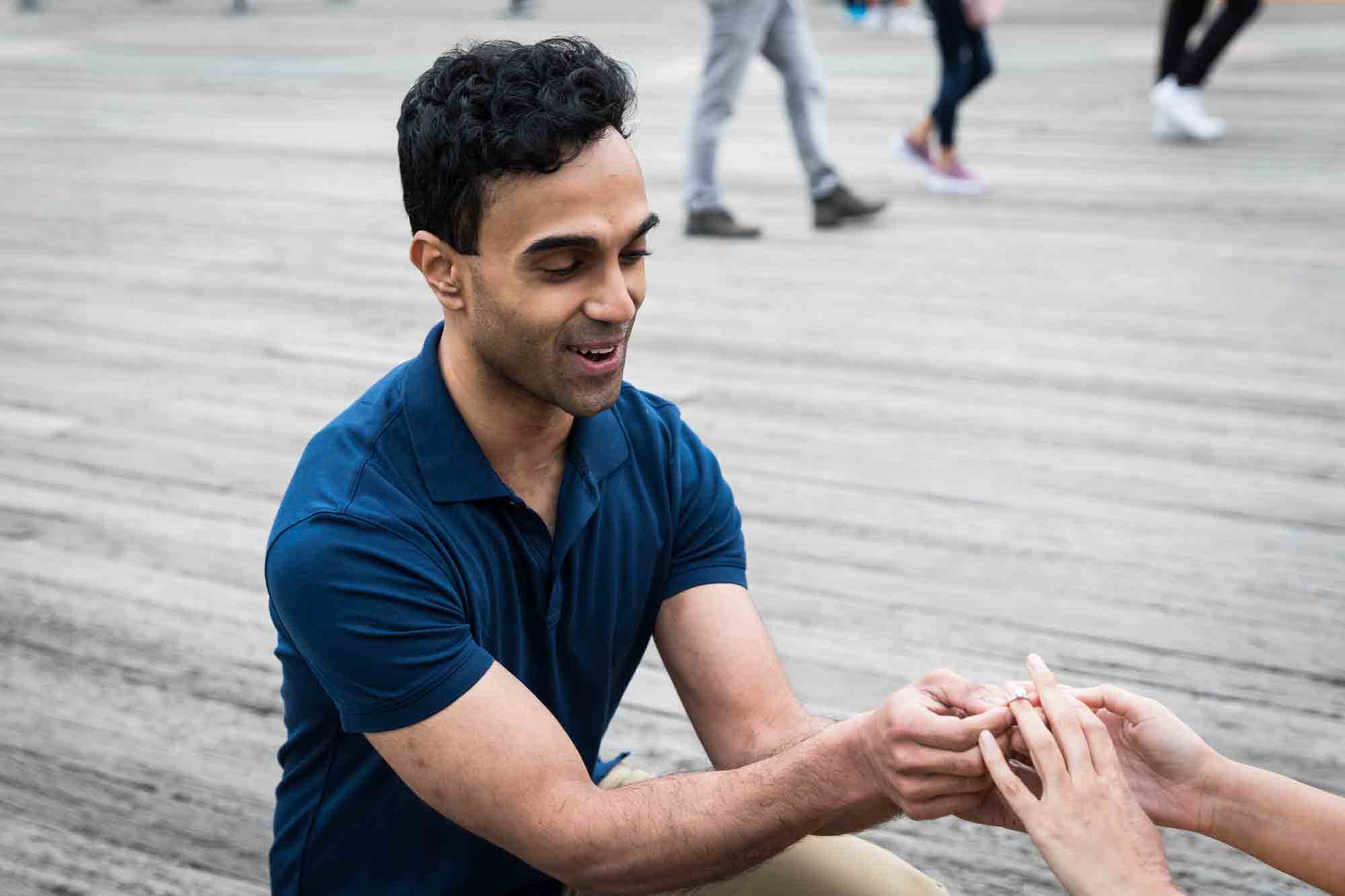 Man proposing to woman on a bench on a dock in Brooklyn Bridge Park