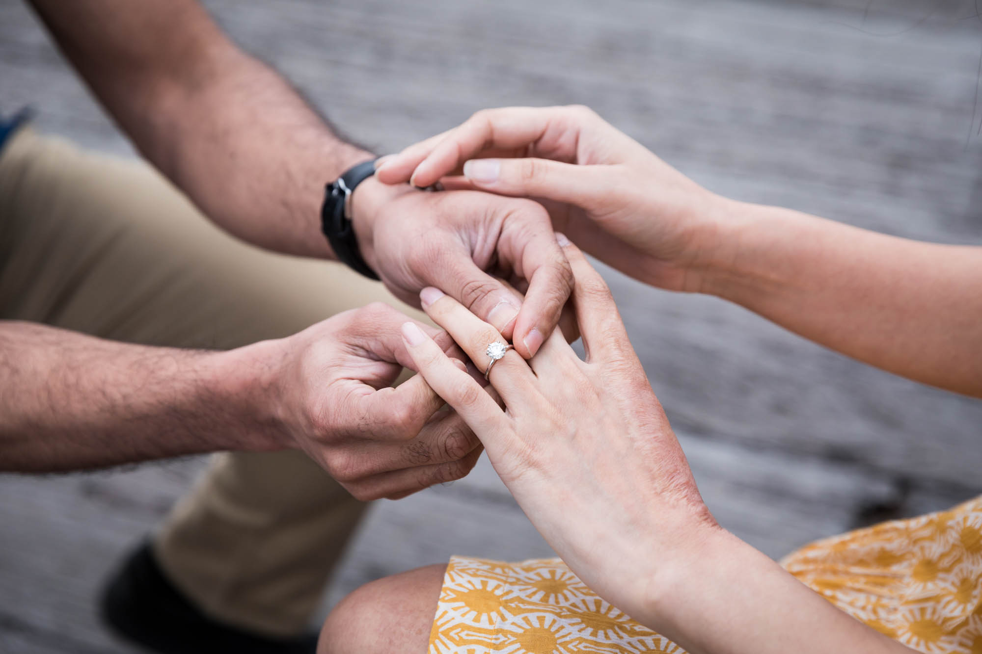 Close up of man putting engagement ring on woman's finger