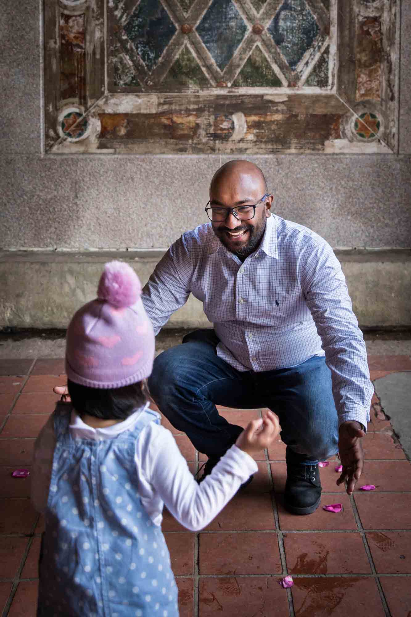 Little girl running to her father under Bethesda Terrace during a Central Park family portrait