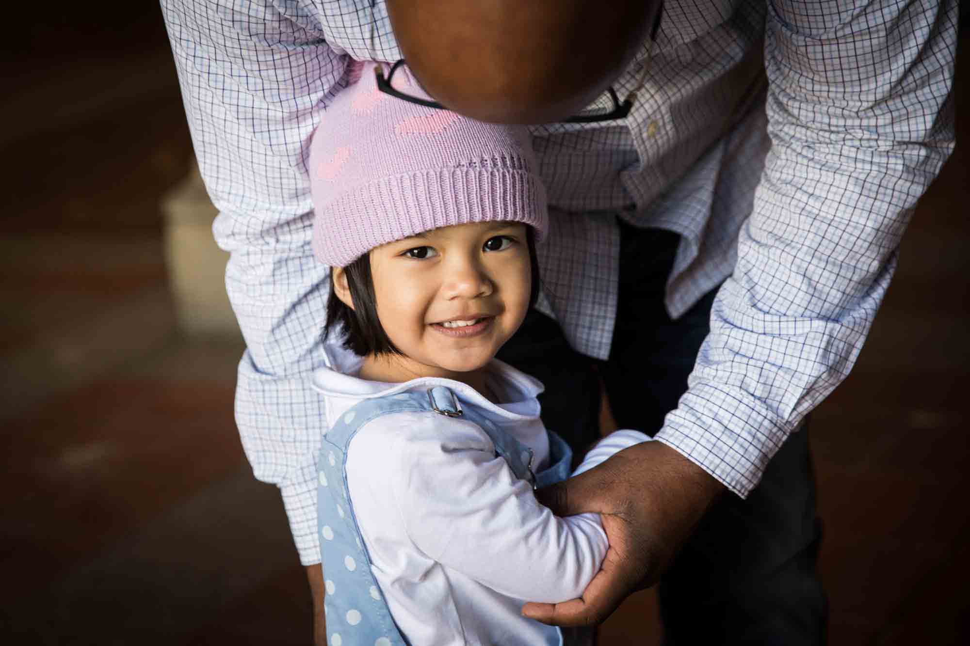 Little girl wearing pink knit cap and white shirt during a Central Park family portrait