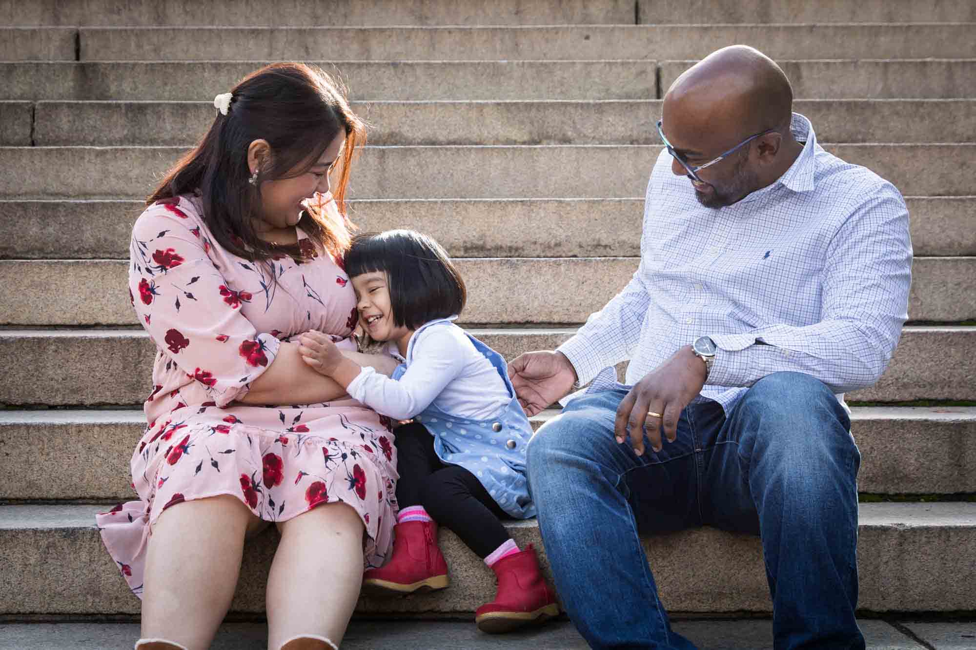 Family laughing and tickling on steps of Bethesda Terrace for an article on Central Park winter portrait tips
