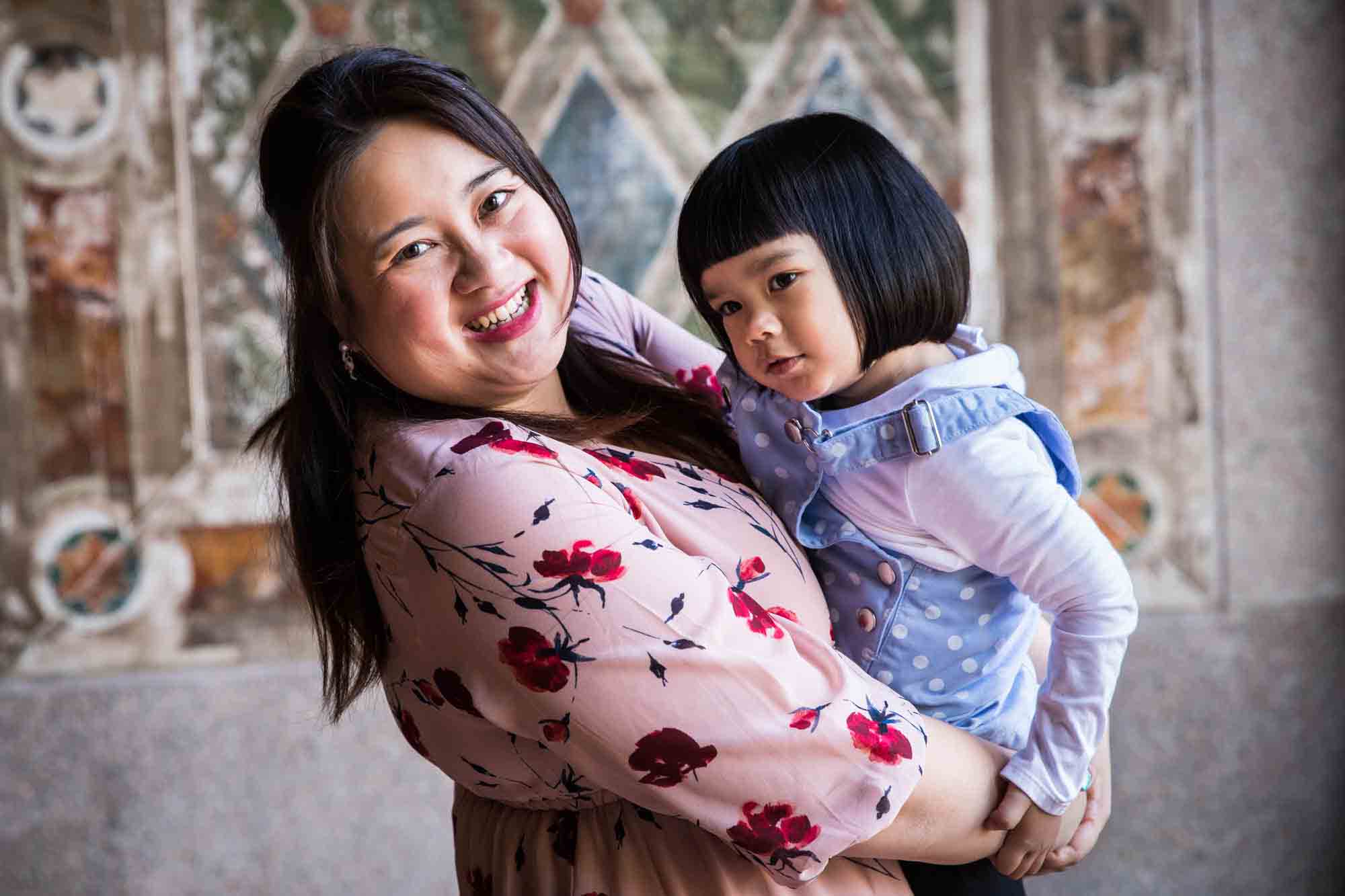 Little girl hugging her mother under Bethesda Terrace during a Central Park family portrait