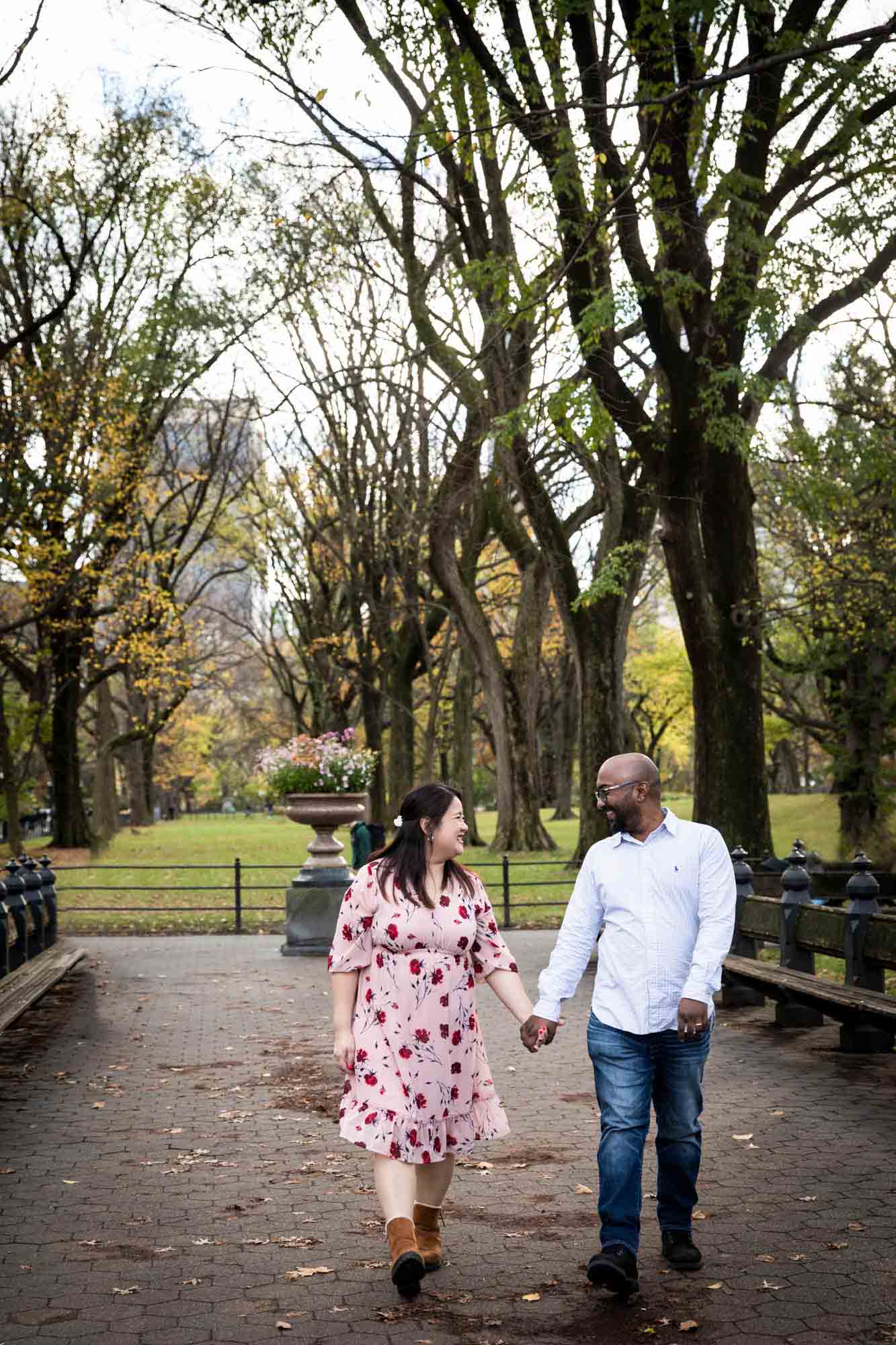 Parents holding hands and walking pathway of Mall for an article on Central Park winter portrait tips