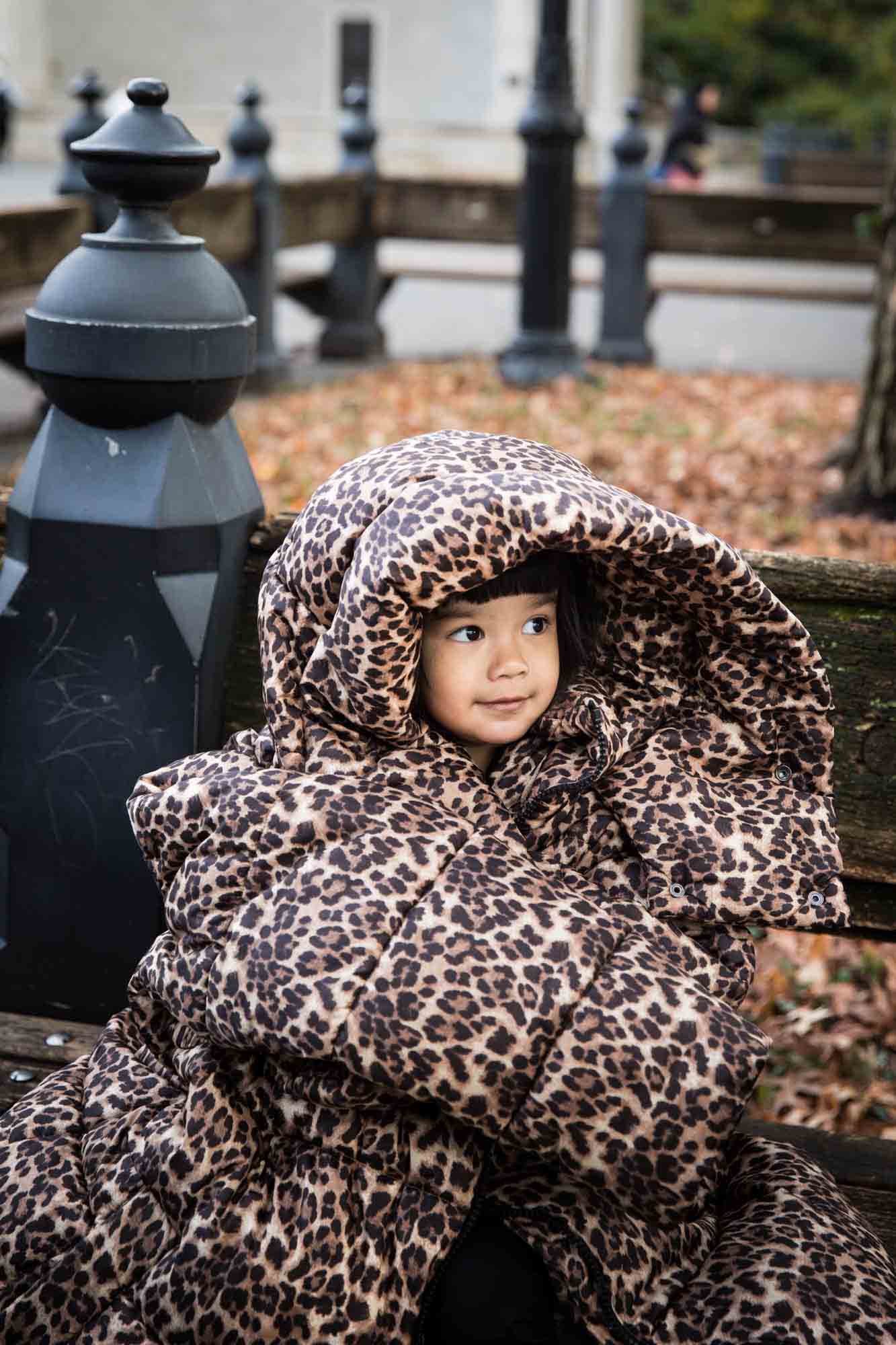 Little girl wrapped in leopard-print coat for an article on Central Park winter portrait tips