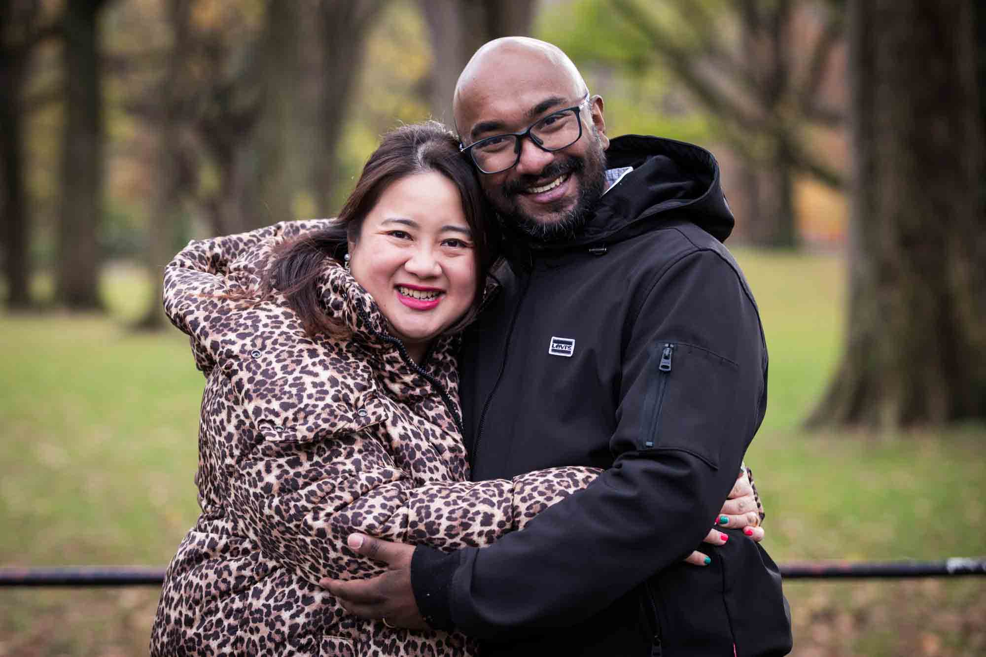 Central Park family portrait of couple hugging while wearing winter coats