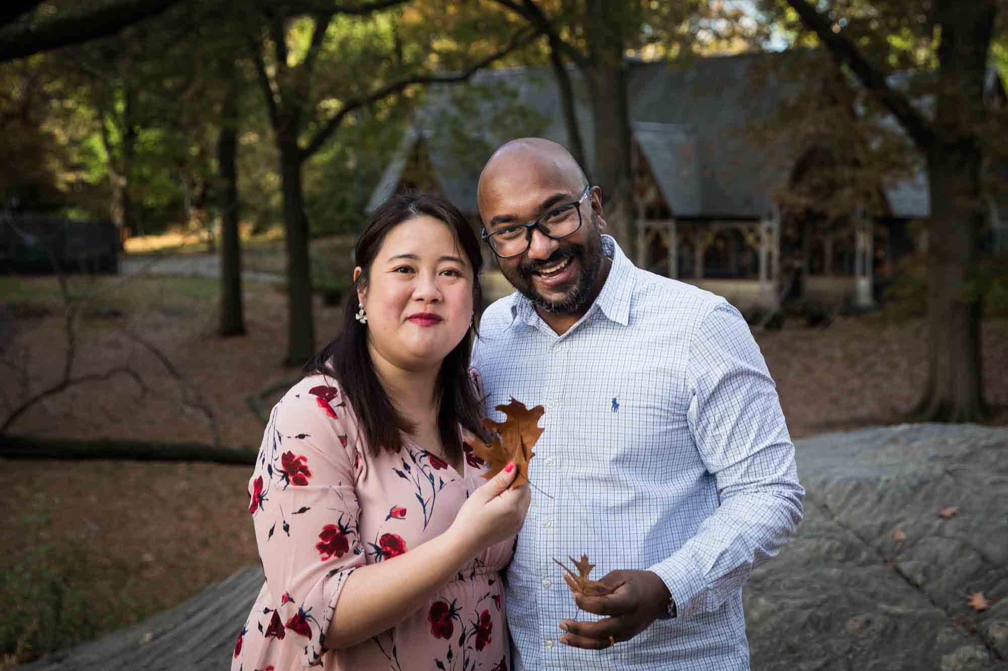 Central Park family portrait of couple holding fall leaves