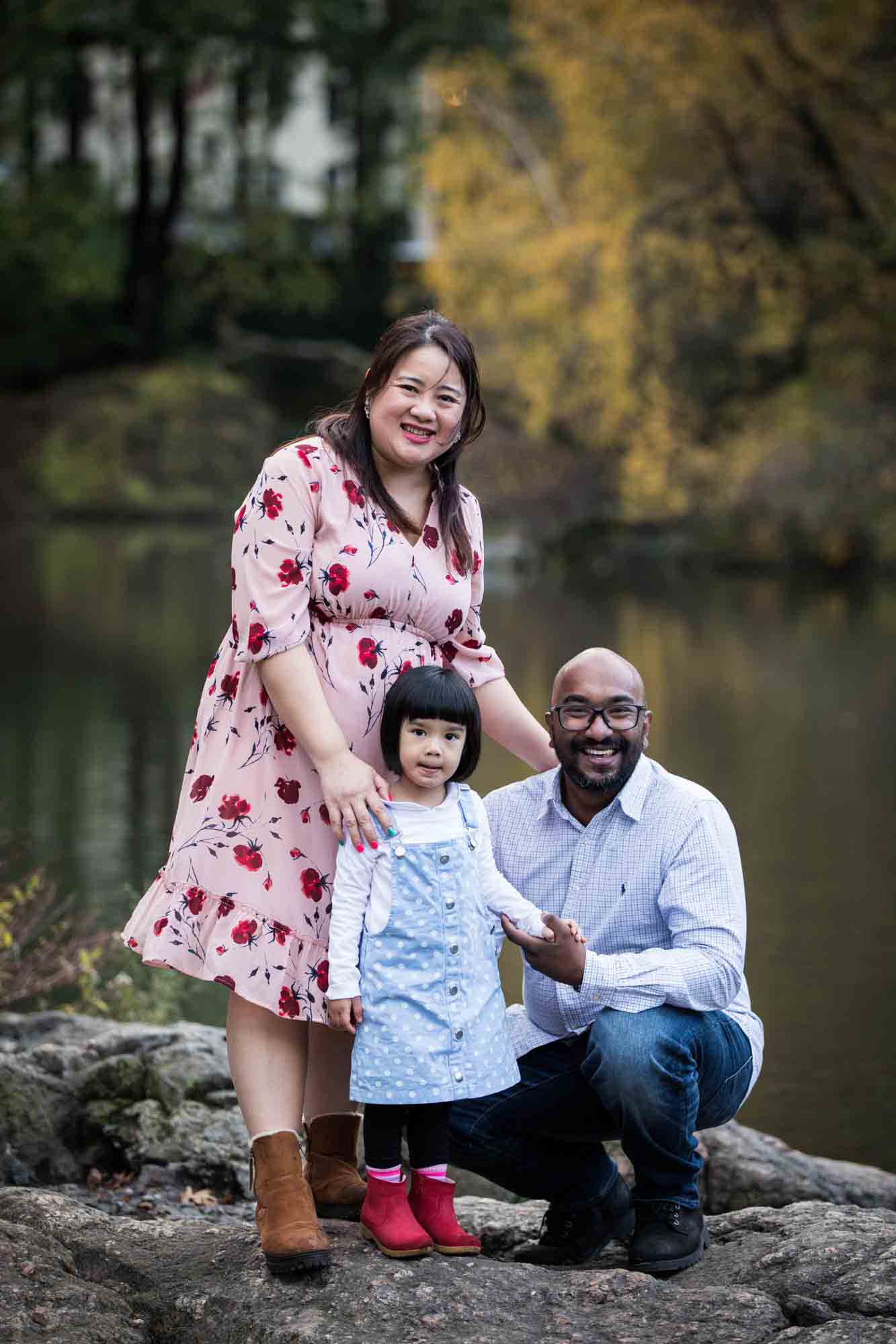 Central Park portrait of family on rocks at edge of Central Park Pond