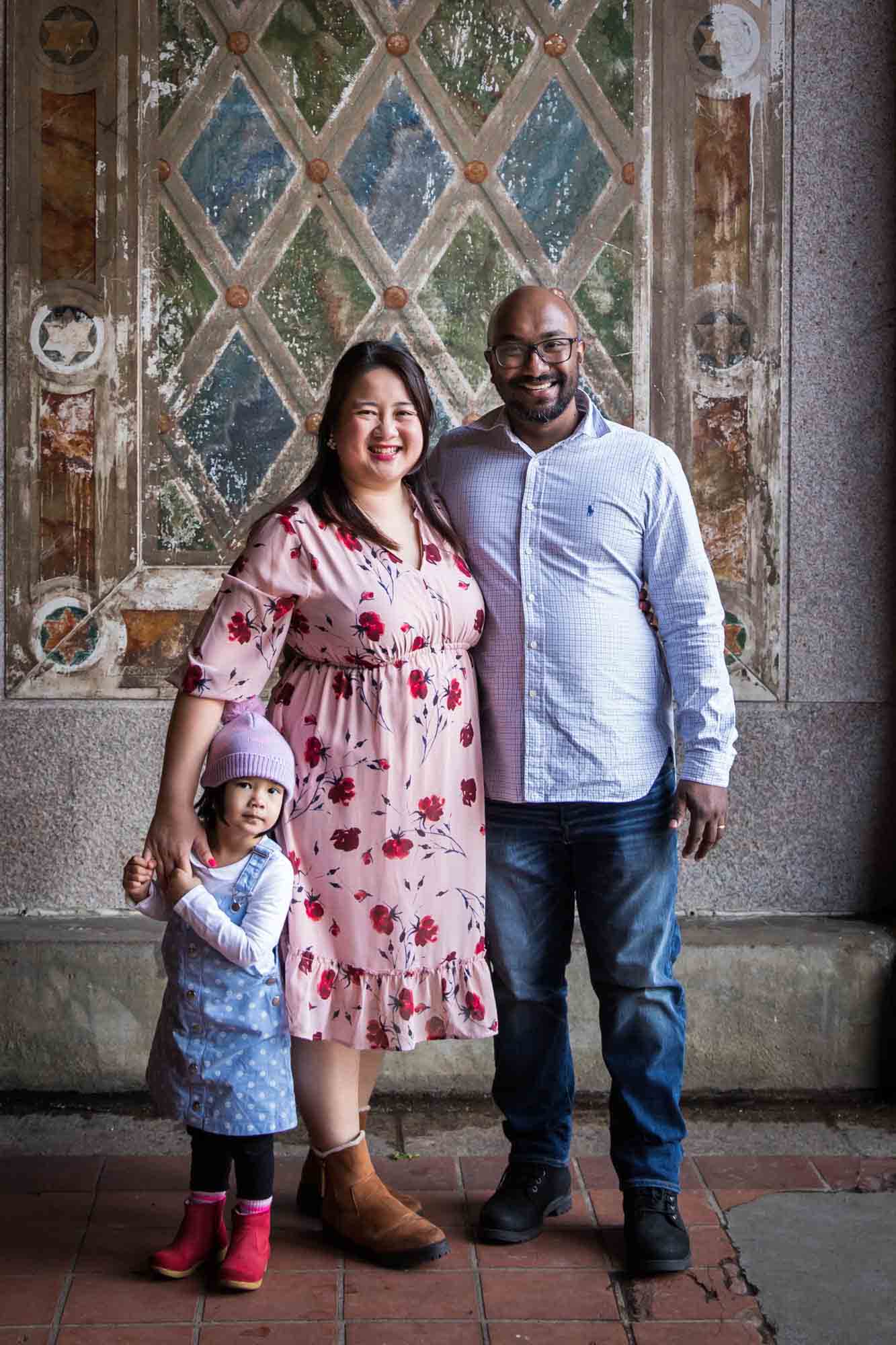 Parents with little girl under Bethesda Terrace during a Central Park family portrait