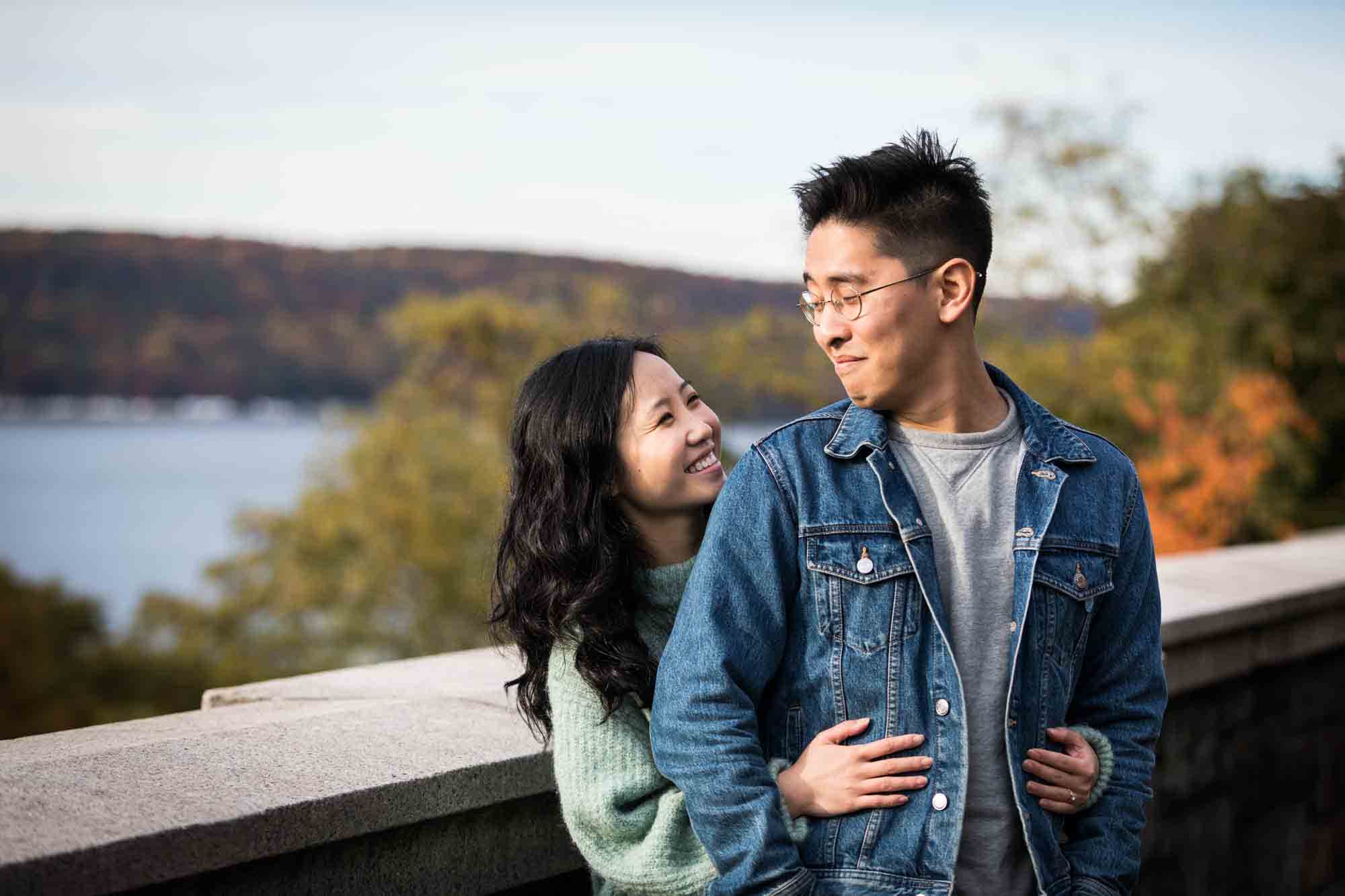Fort Tryon Park engagement photo of woman hugging man from behind on Billings Terrace