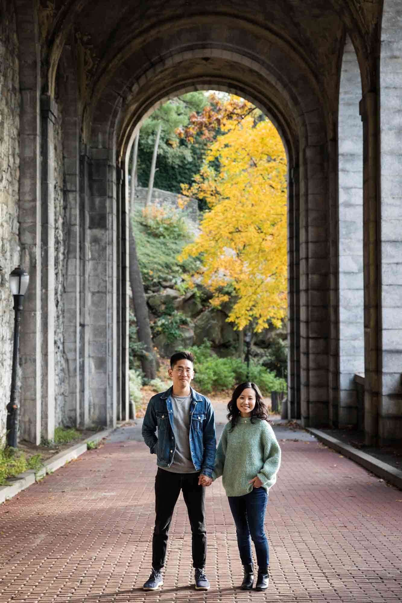 Fort Tryon Park engagement photos of couple holding hands under Billings Arcade