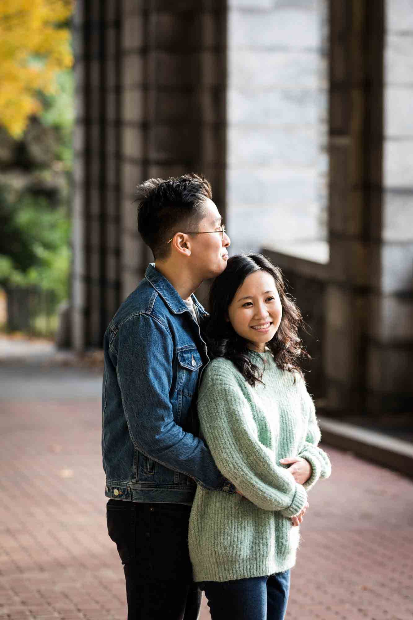 Couple hugging under Billings Arcade at a Fort Tryon Park engagement photo shoot