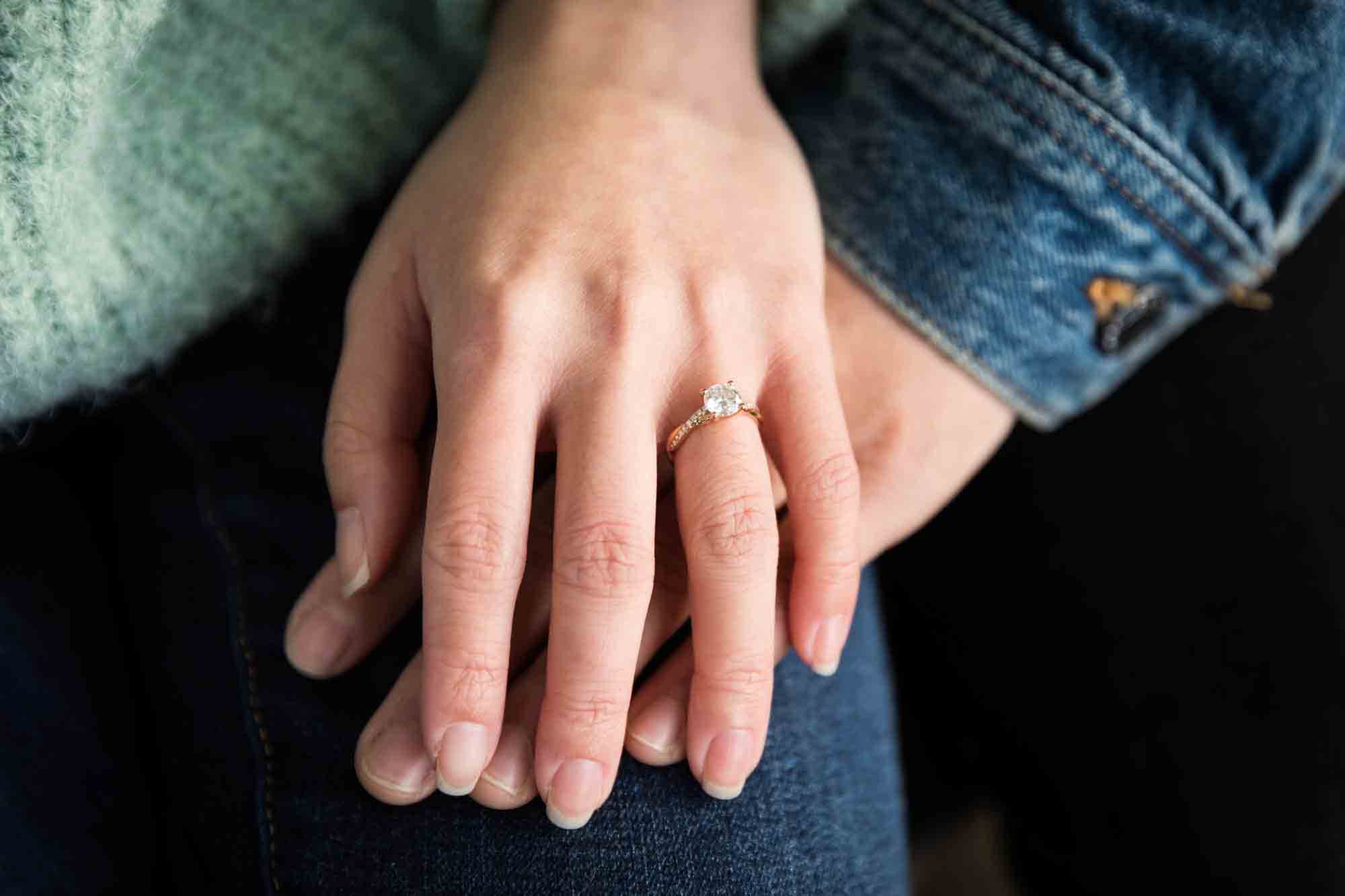 Hand of woman wearing engagement ring on top of man's hand