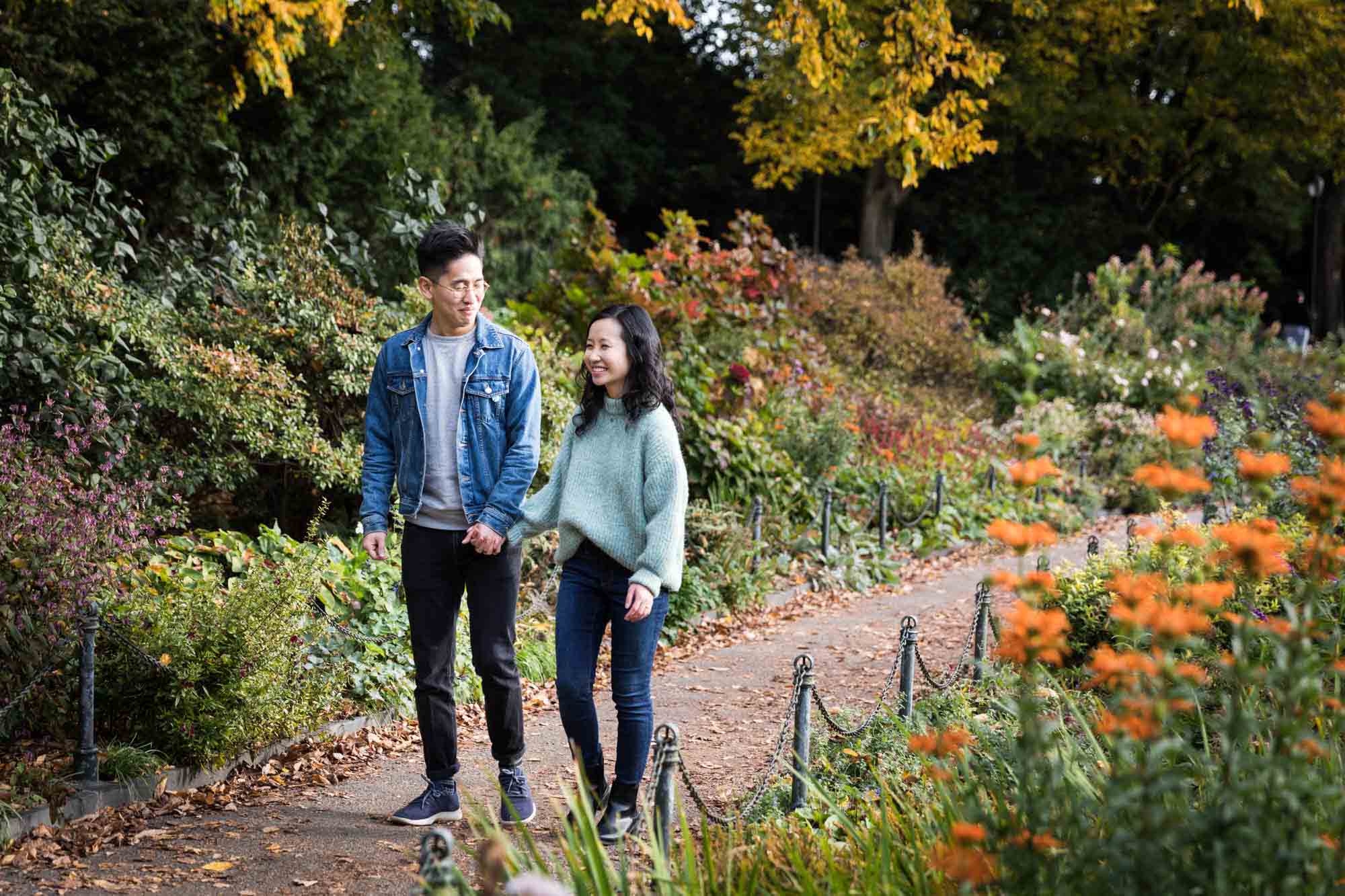 Fort Tryon Park engagement photo of couple walking while holding hands in Heather Garden