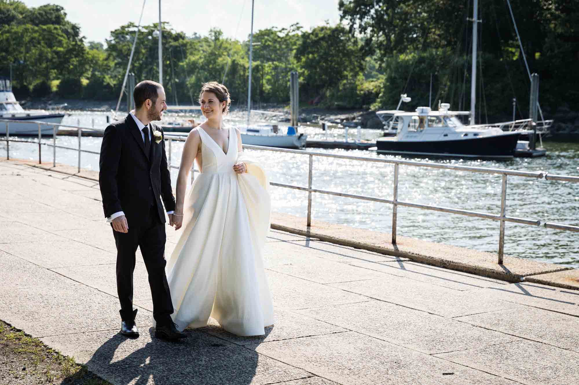 Glen Island Harbour Club wedding photos of bride and groom walking on path in front of water and boats
