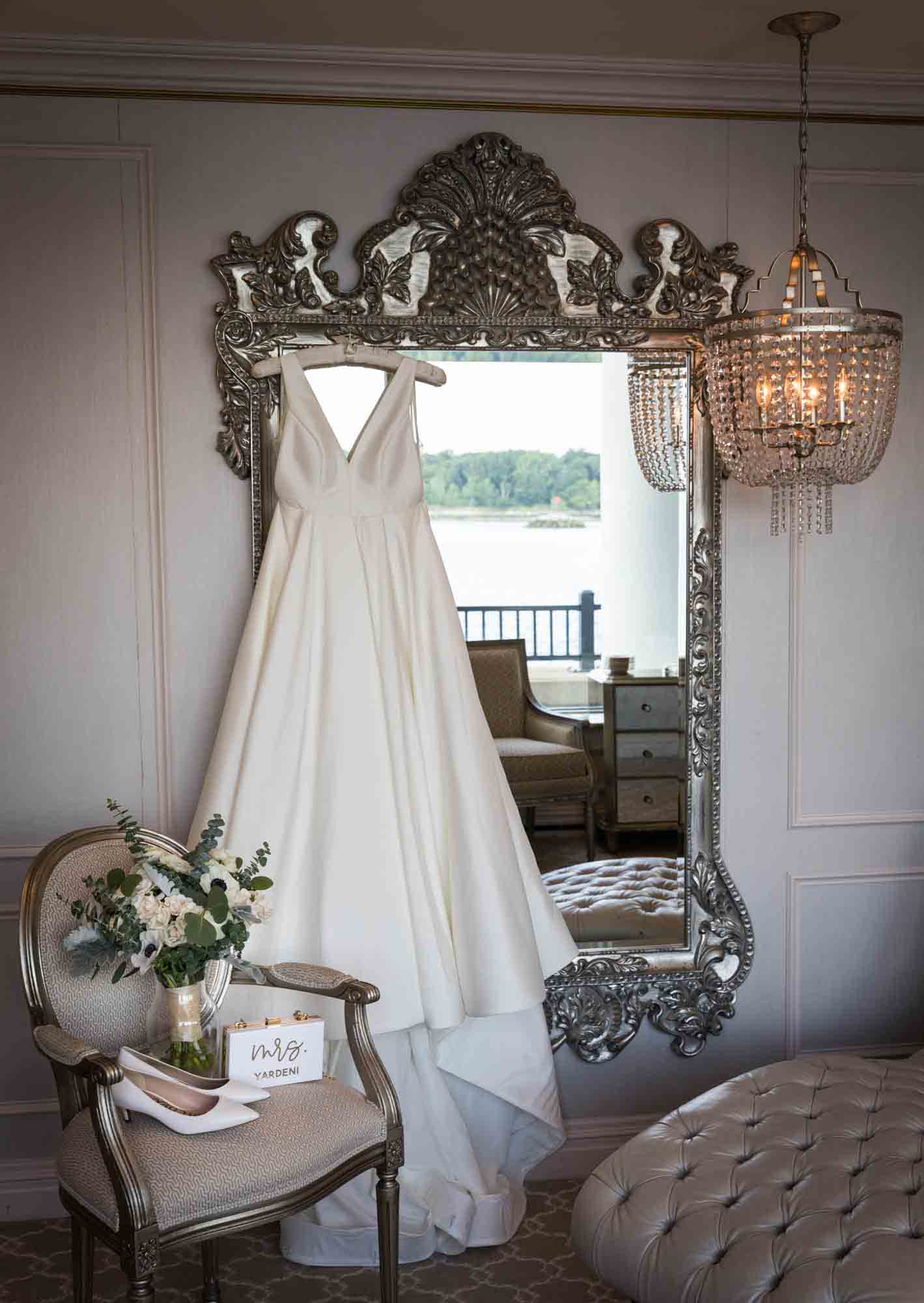 Wedding dress hanging on elaborate mirror with chandolier in Glen Island Harbour Club bridal suite