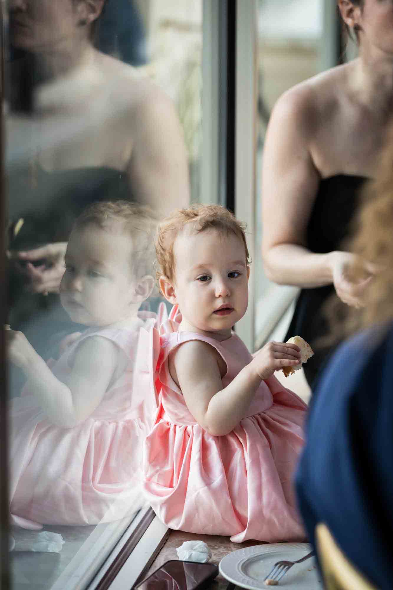 Baby girl in pink dress reflected in window at a Glen Island Harbour Club wedding