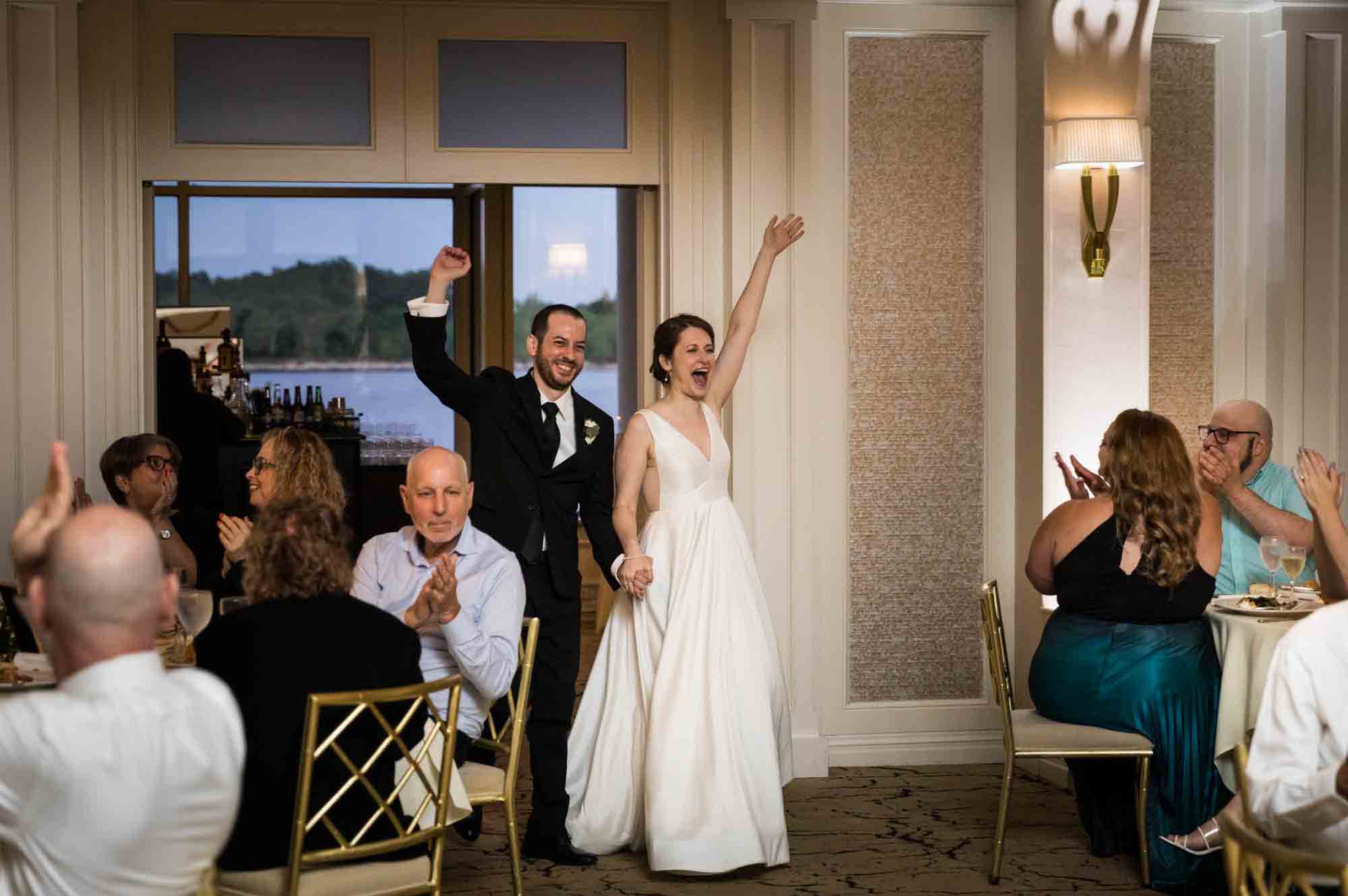 Bride and groom entering reception with hands raised at a Glen Island Harbour Club wedding