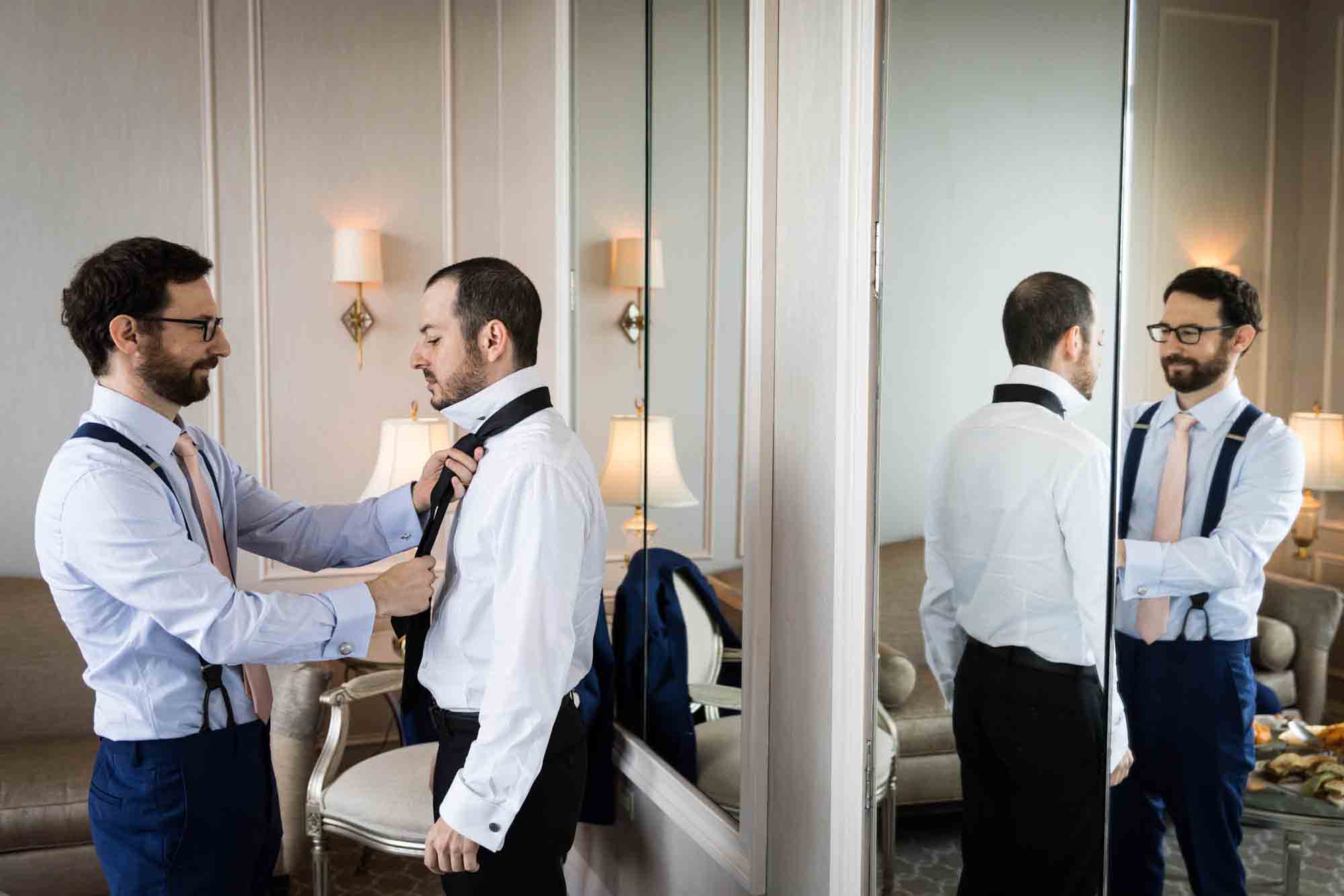 Best man adjusting tie of groom reflected in mirror