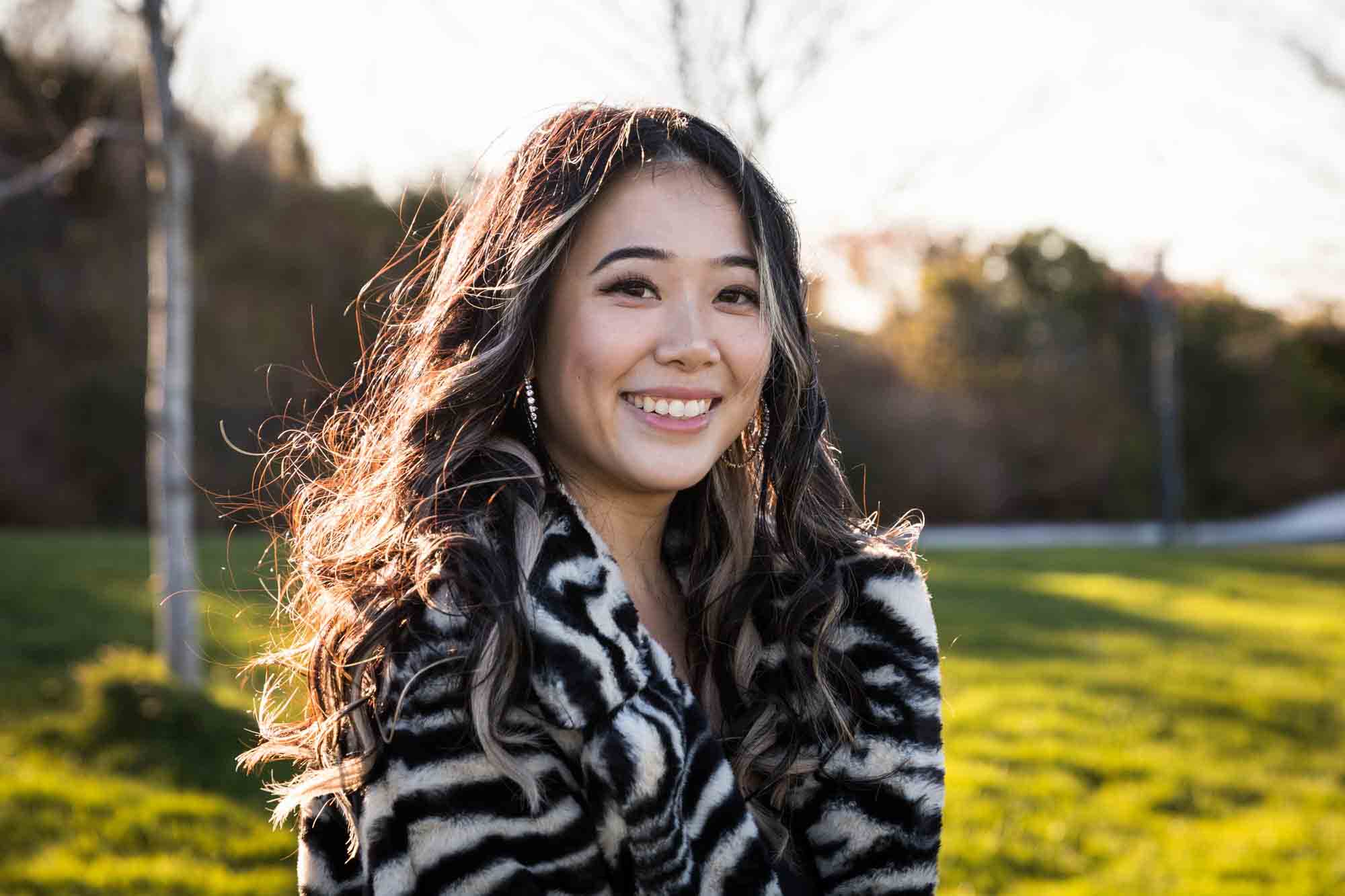 Smiling woman with long hair wearing zebra-print coat on Governors Island