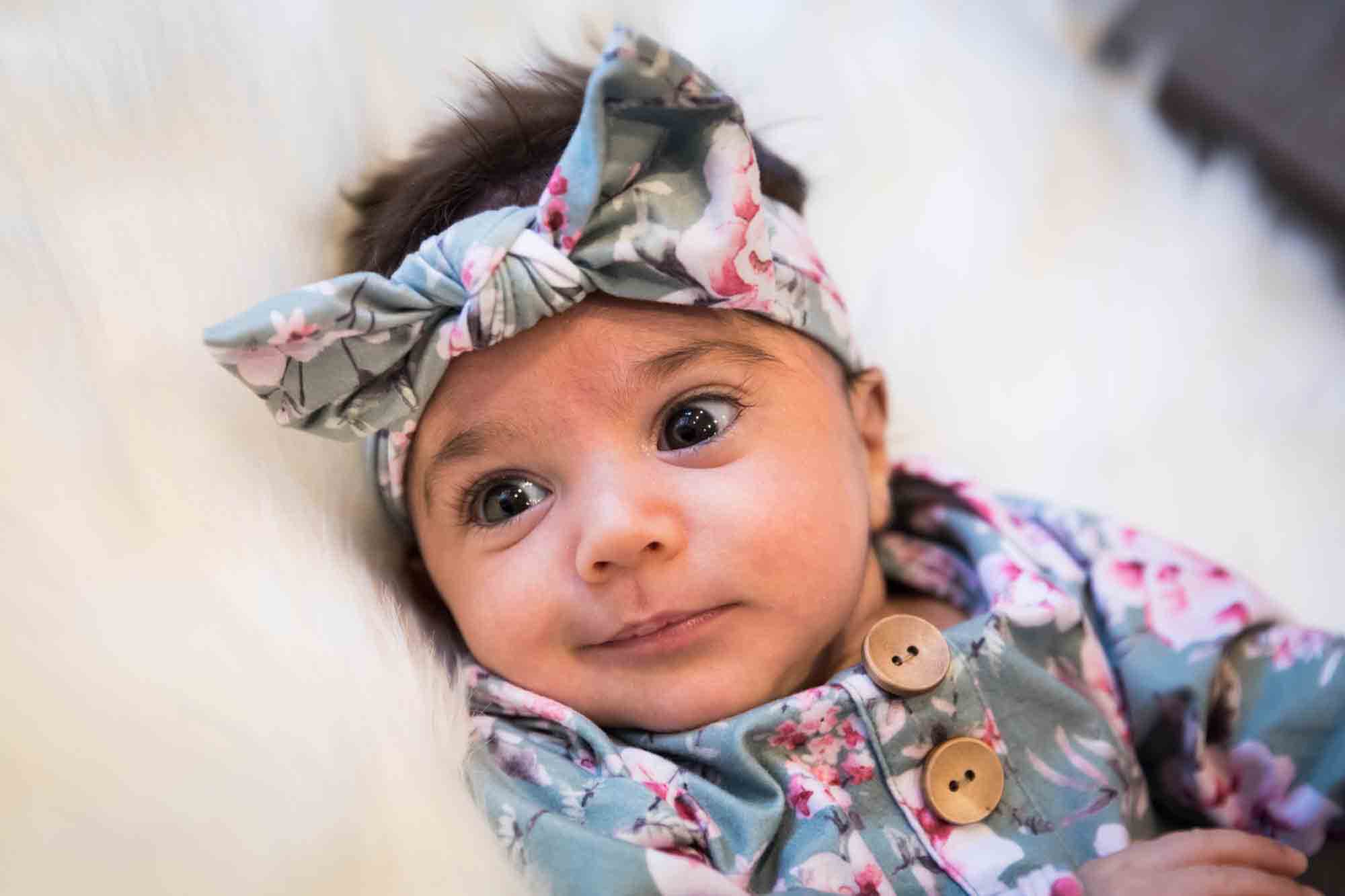 Newborn baby wearing floral dress and headband during a Christmas-themed newborn photo shoot in NYC