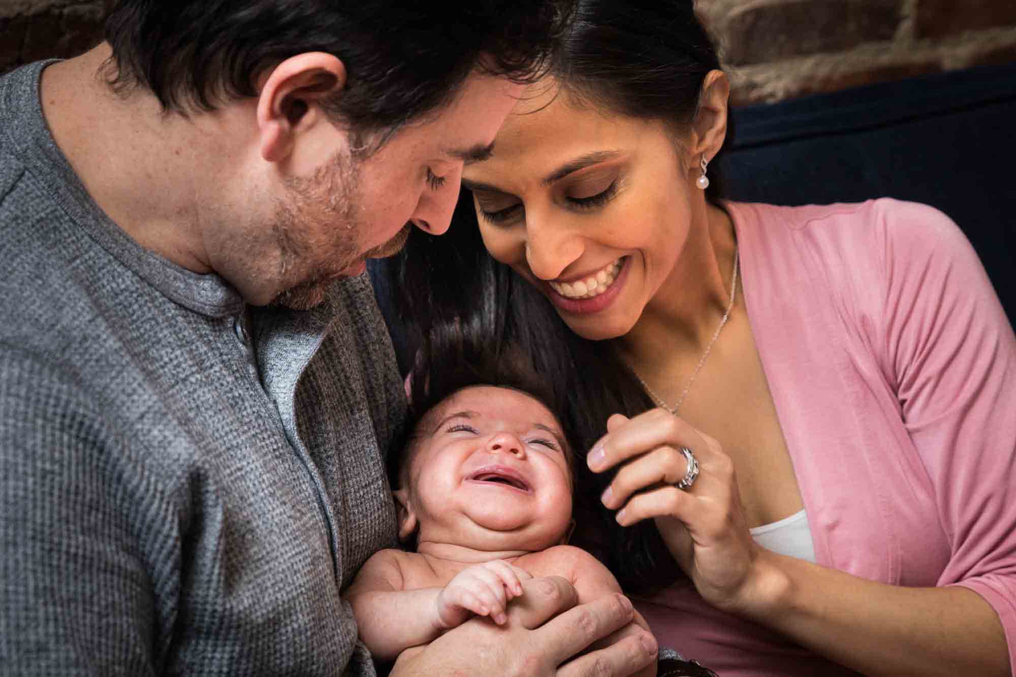 Newborn baby with wile hair held by father wearing grey sweater