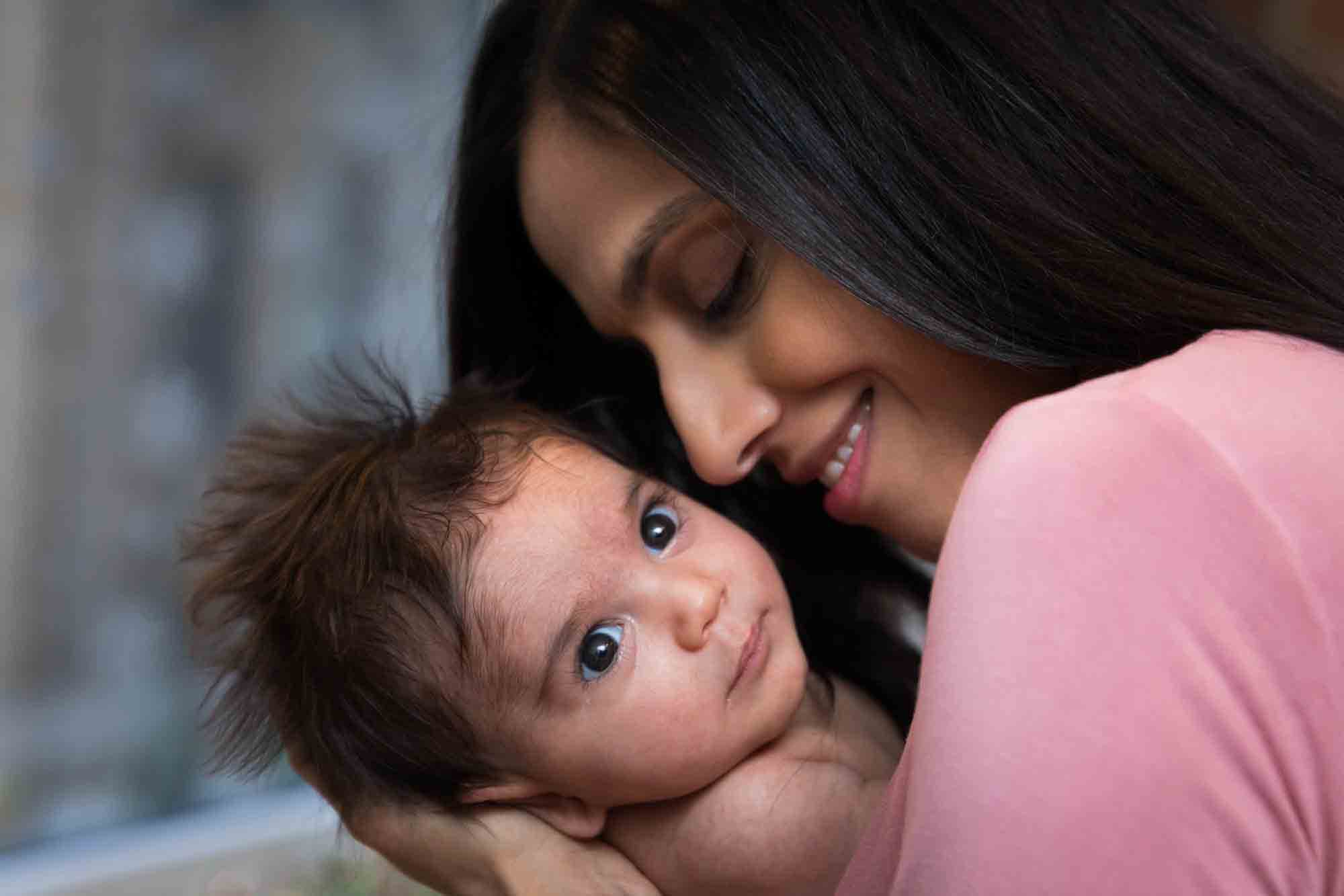 Mother wearing pink shirt holding newborn baby