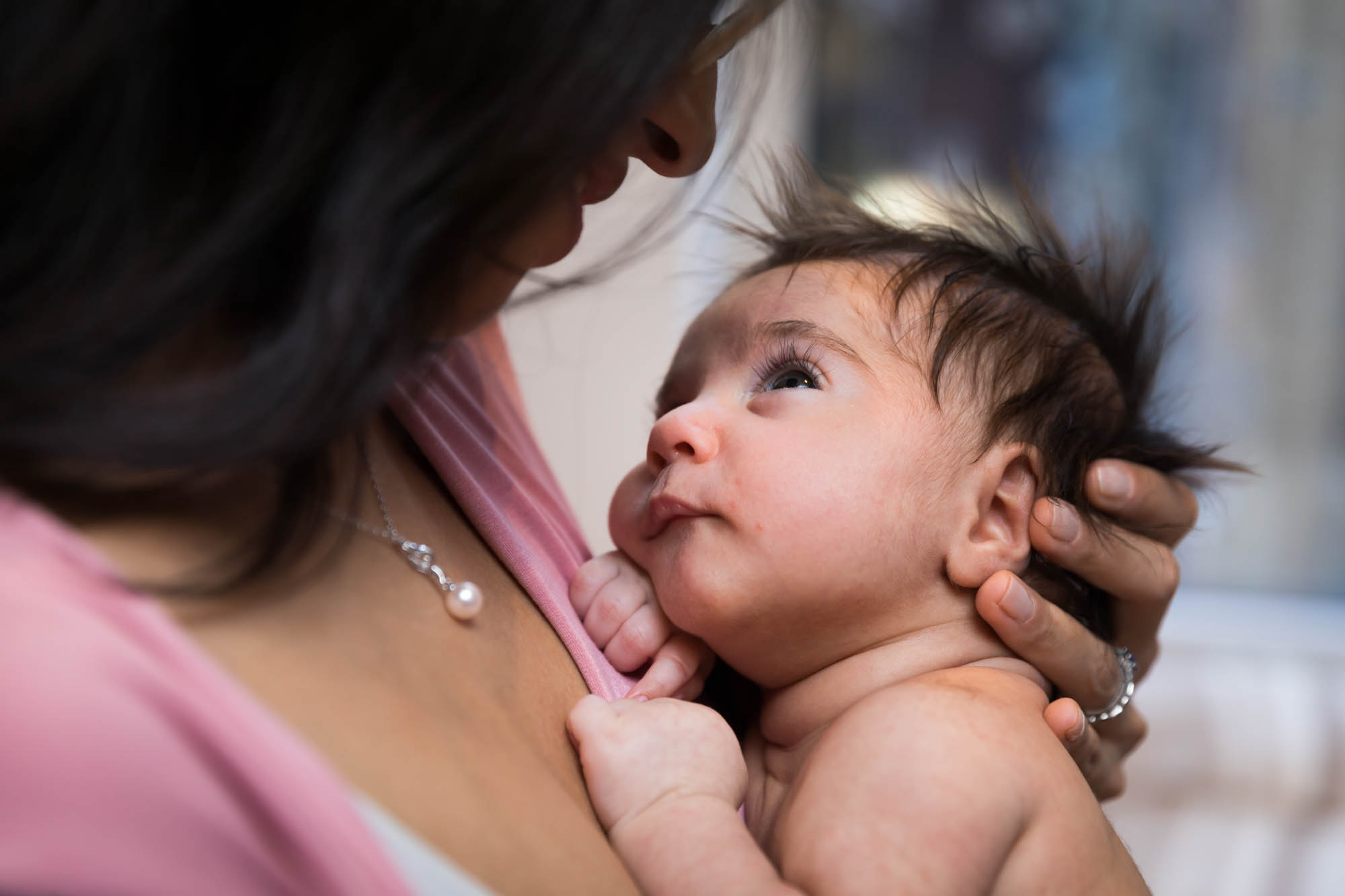 Newborn baby looking up at mother