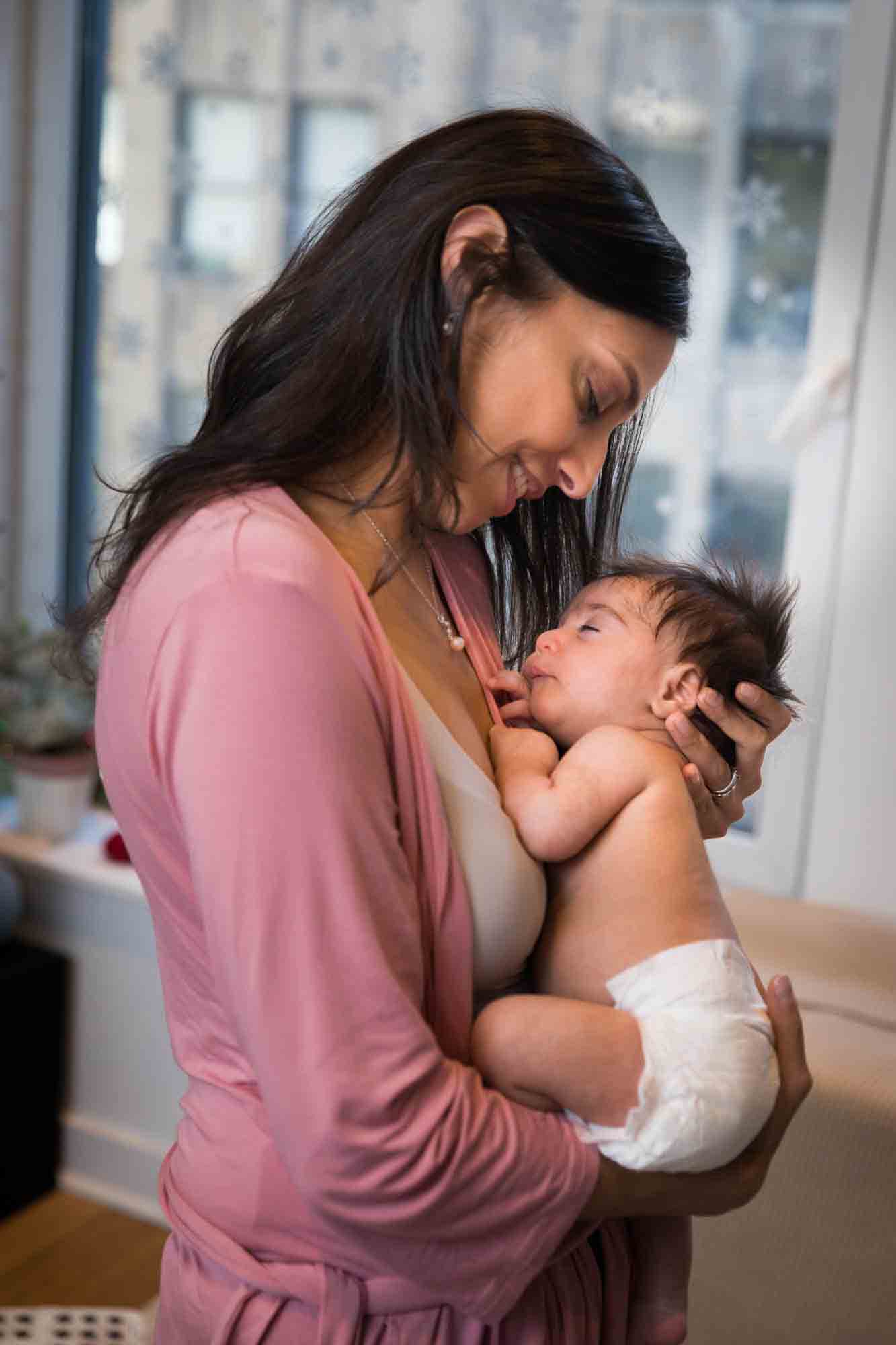 Mother wearing pink shirt holding newborn baby