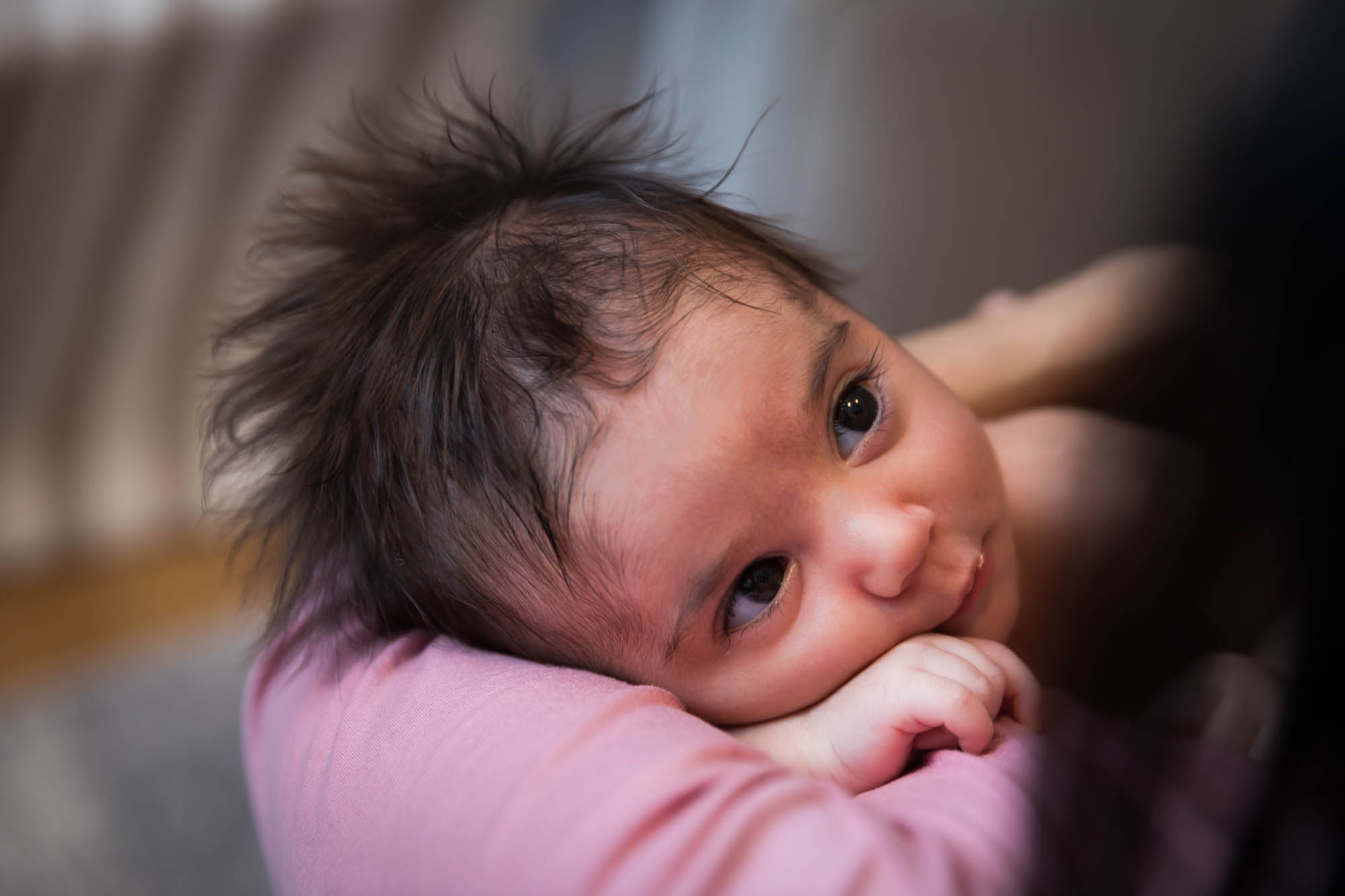 Newborn baby with wild hair looking up at mother