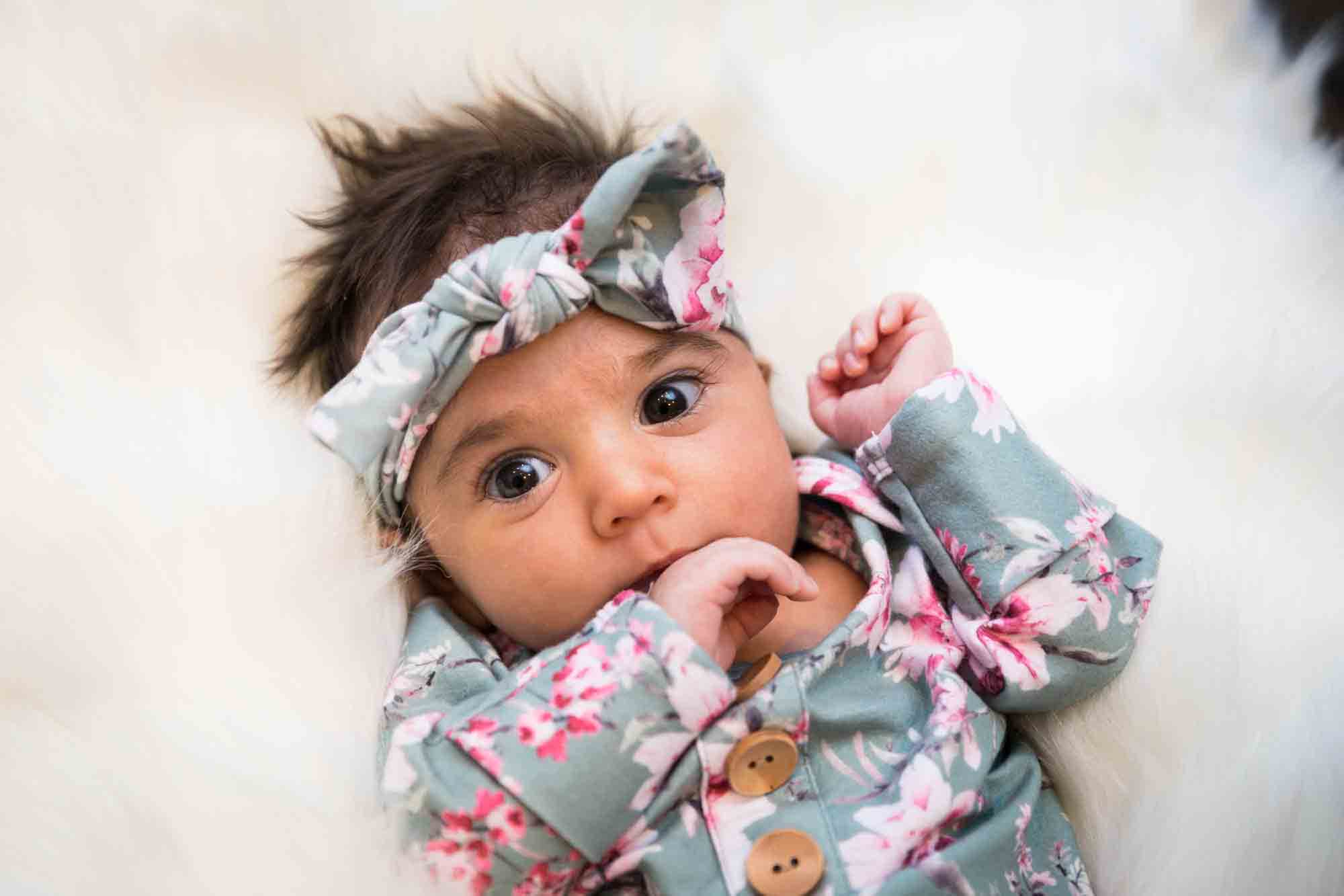 Newborn baby wearing floral dress and headband during a Christmas-themed newborn photo shoot in NYC
