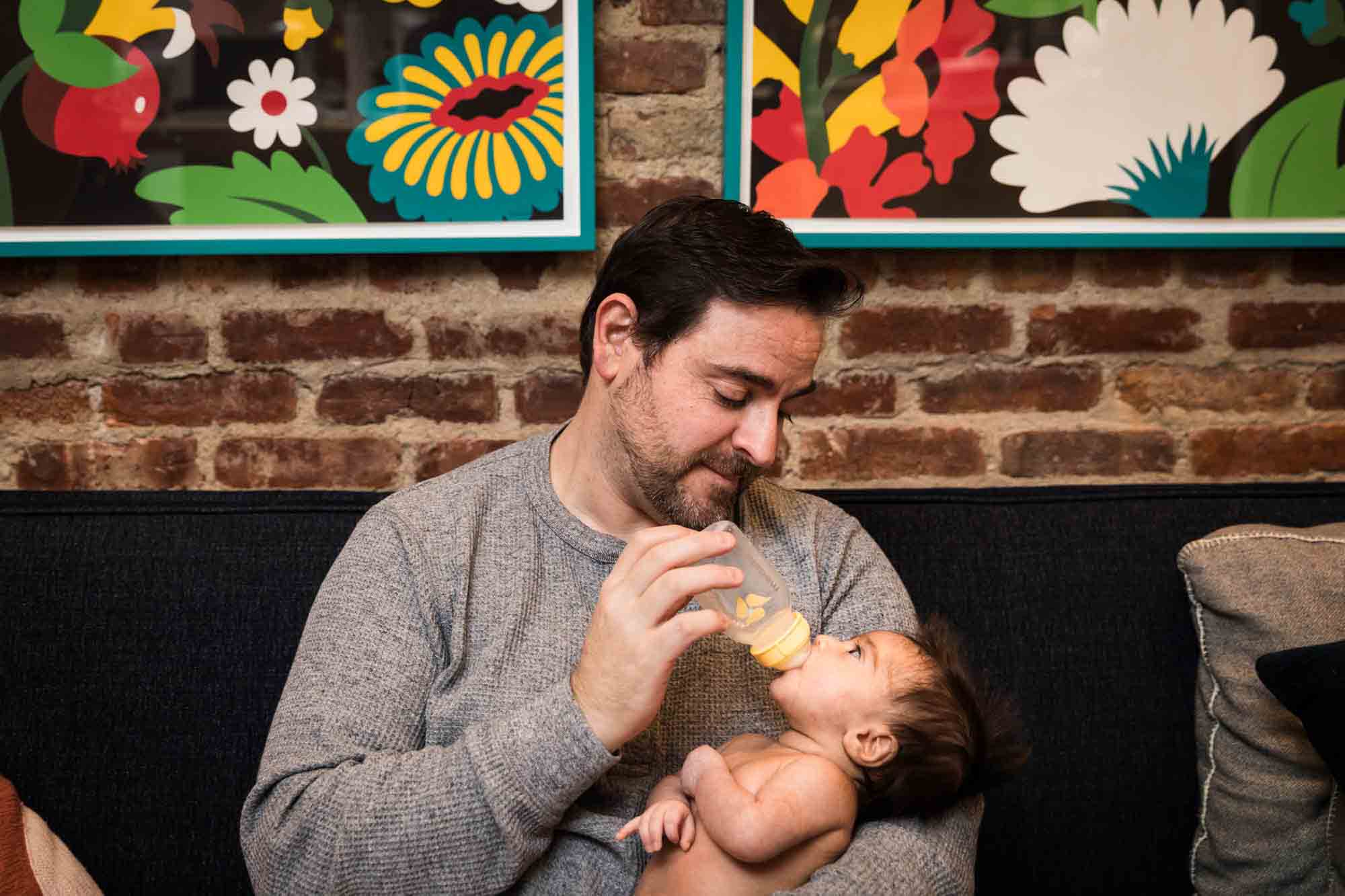 Father feeding a bottle to a newborn baby during a Christmas-themed newborn photo shoot in NYC