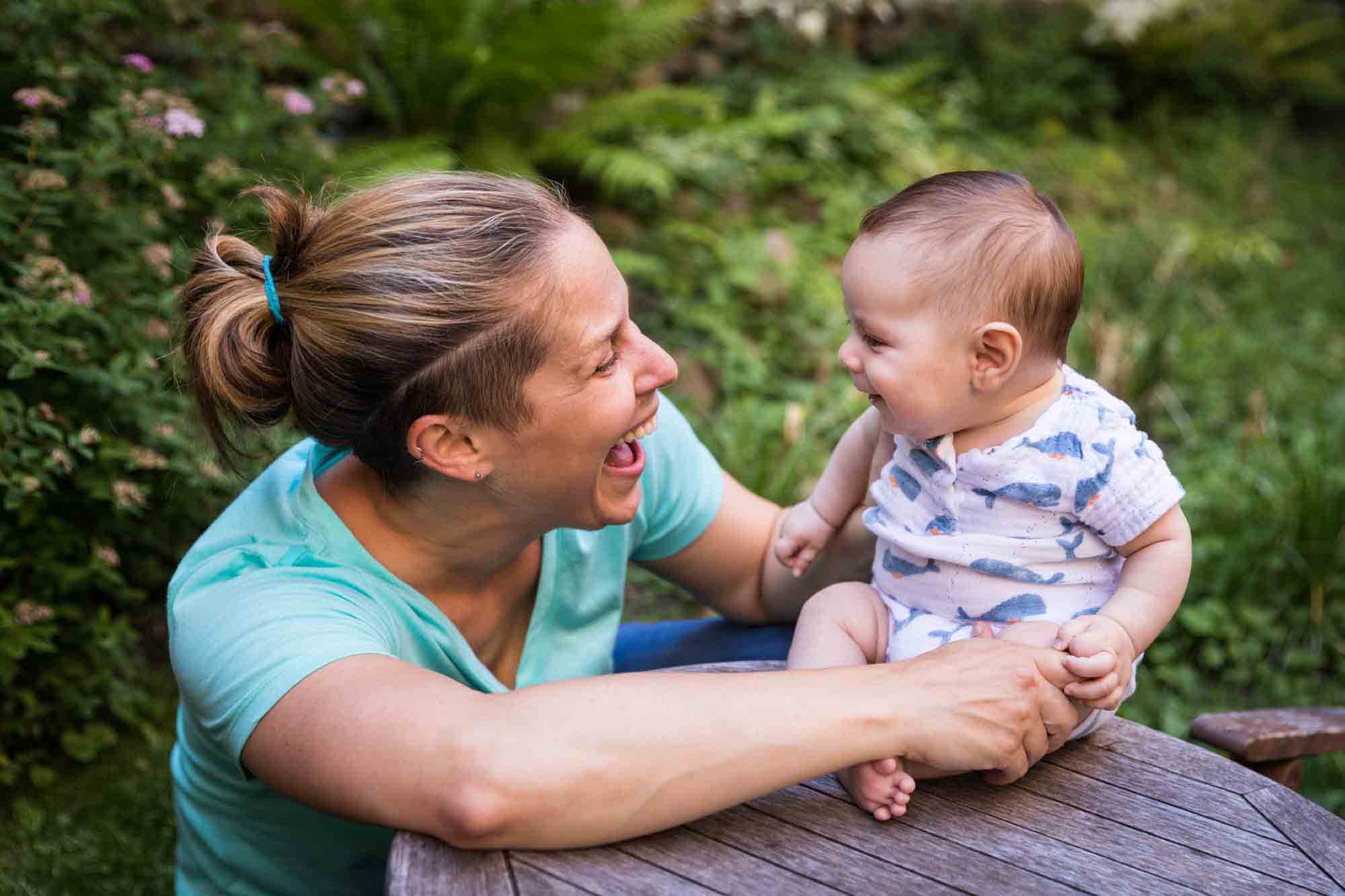 Mother making baby smile while sitting on table