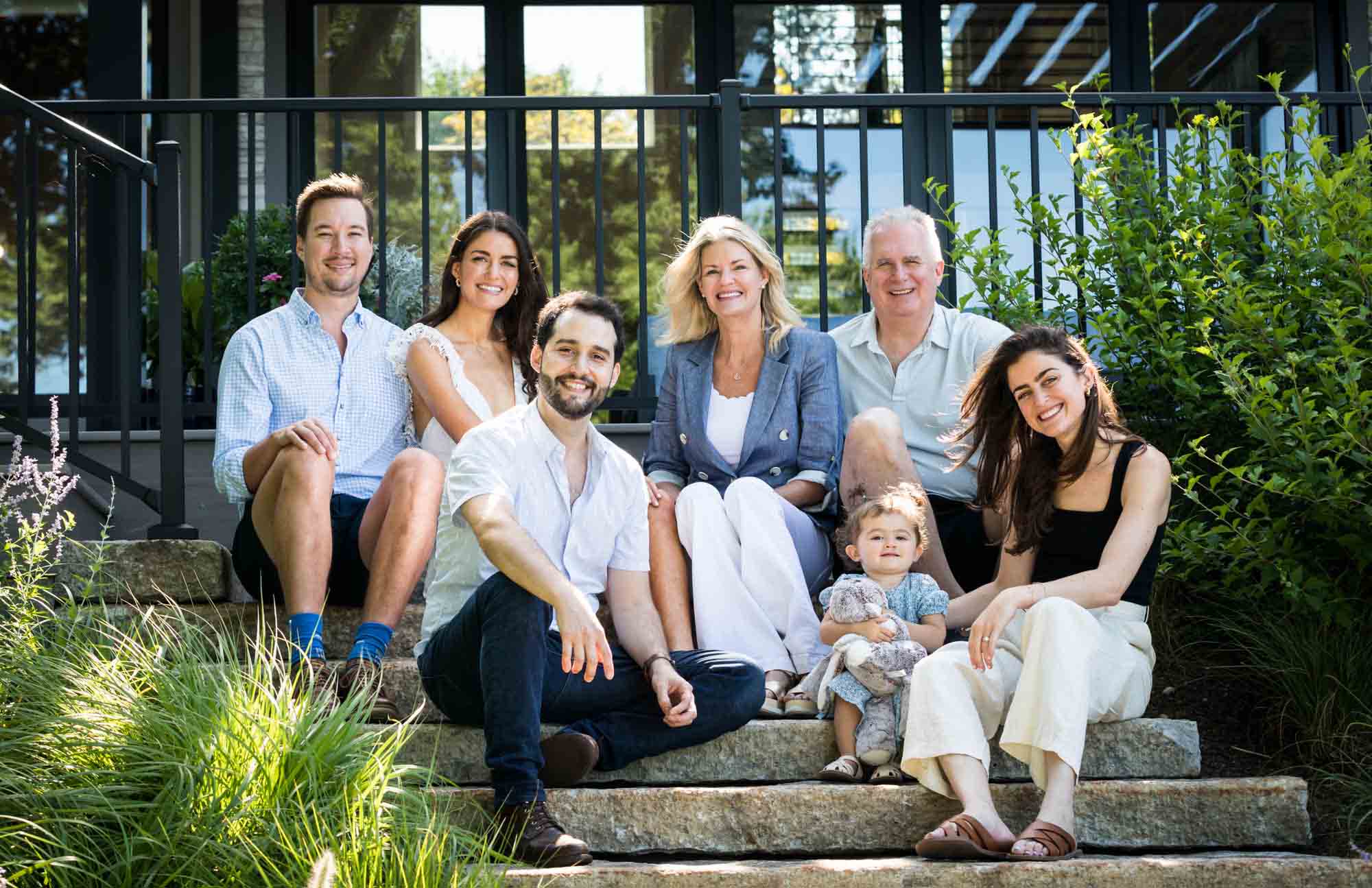 Large family sitting on steps smiling for family portrait