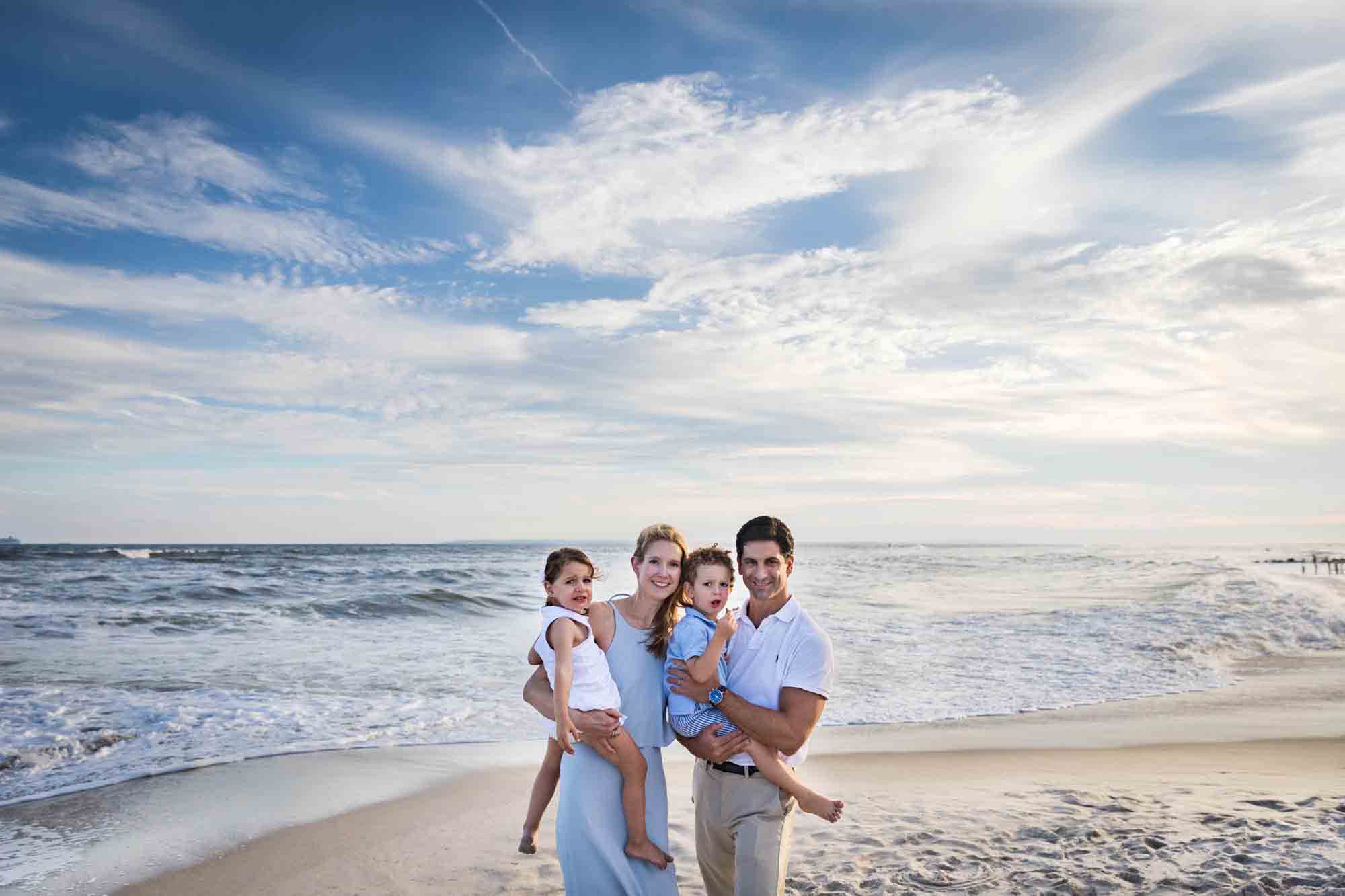Parents holding little boy and girl on beach for an article advertising family portrait gift certificates