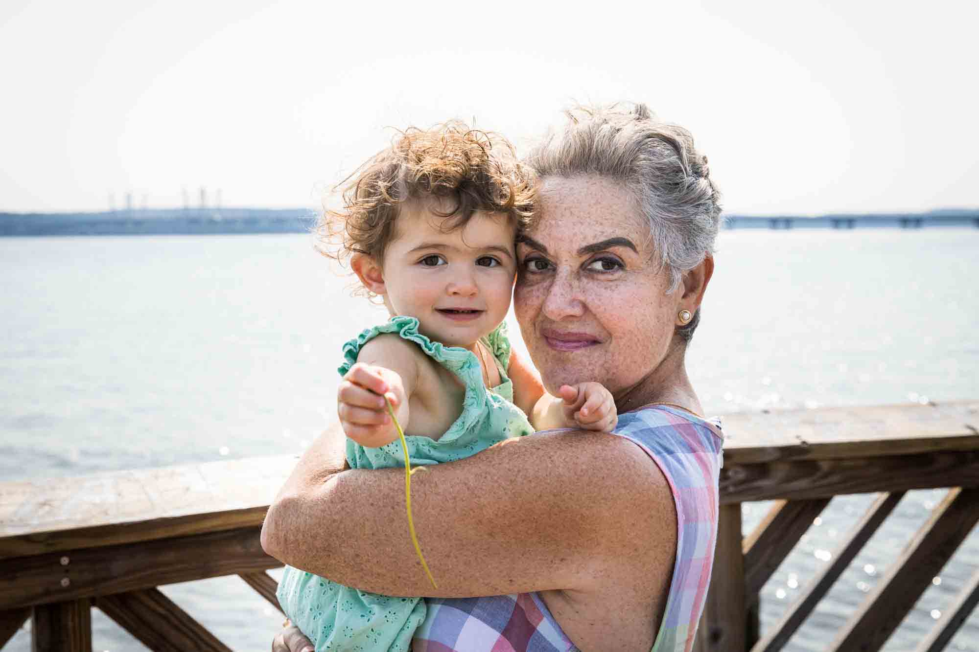 Grandmother holding granddaughter in front of waterfront for an article advertising family portrait gift certificates