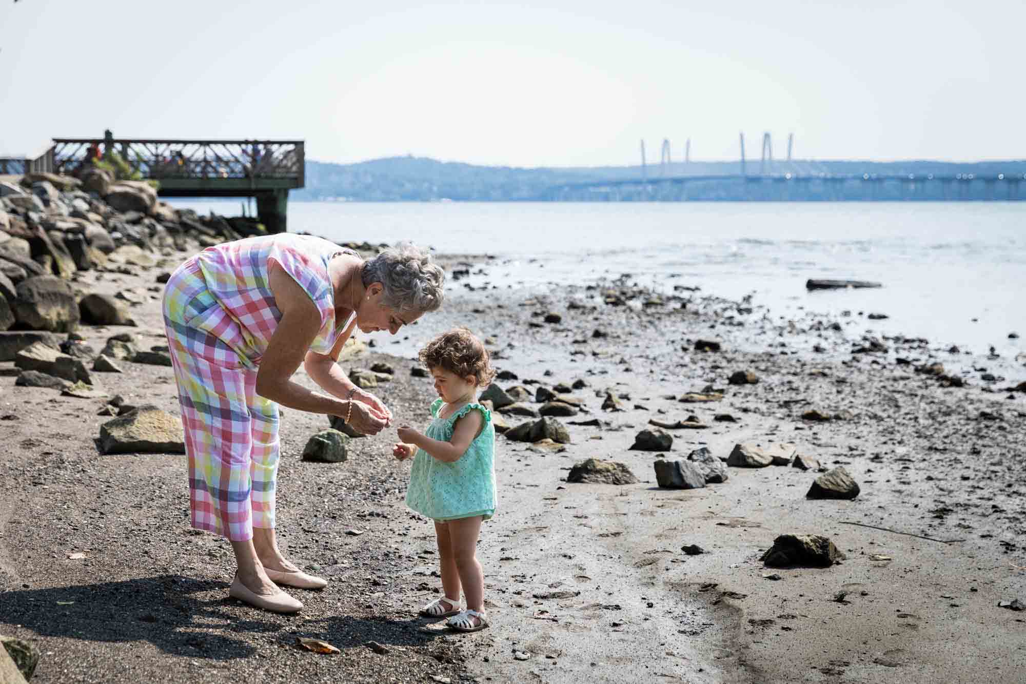 Grandmother showing shell to little girl on beach for an article advertising family portrait gift certificates