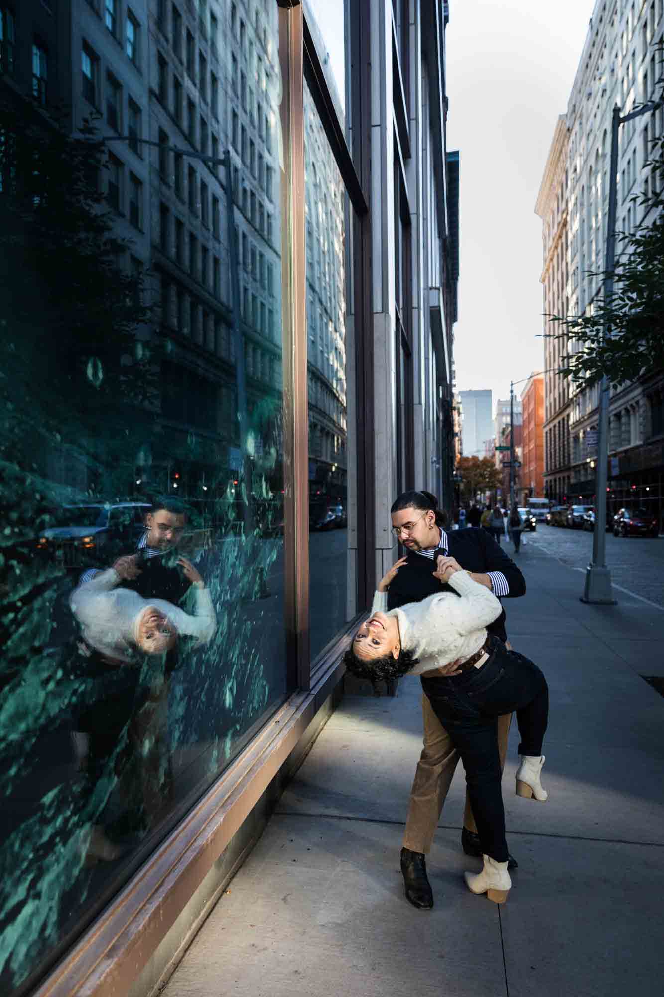 Couple dancing in front of reflective window in NYC
