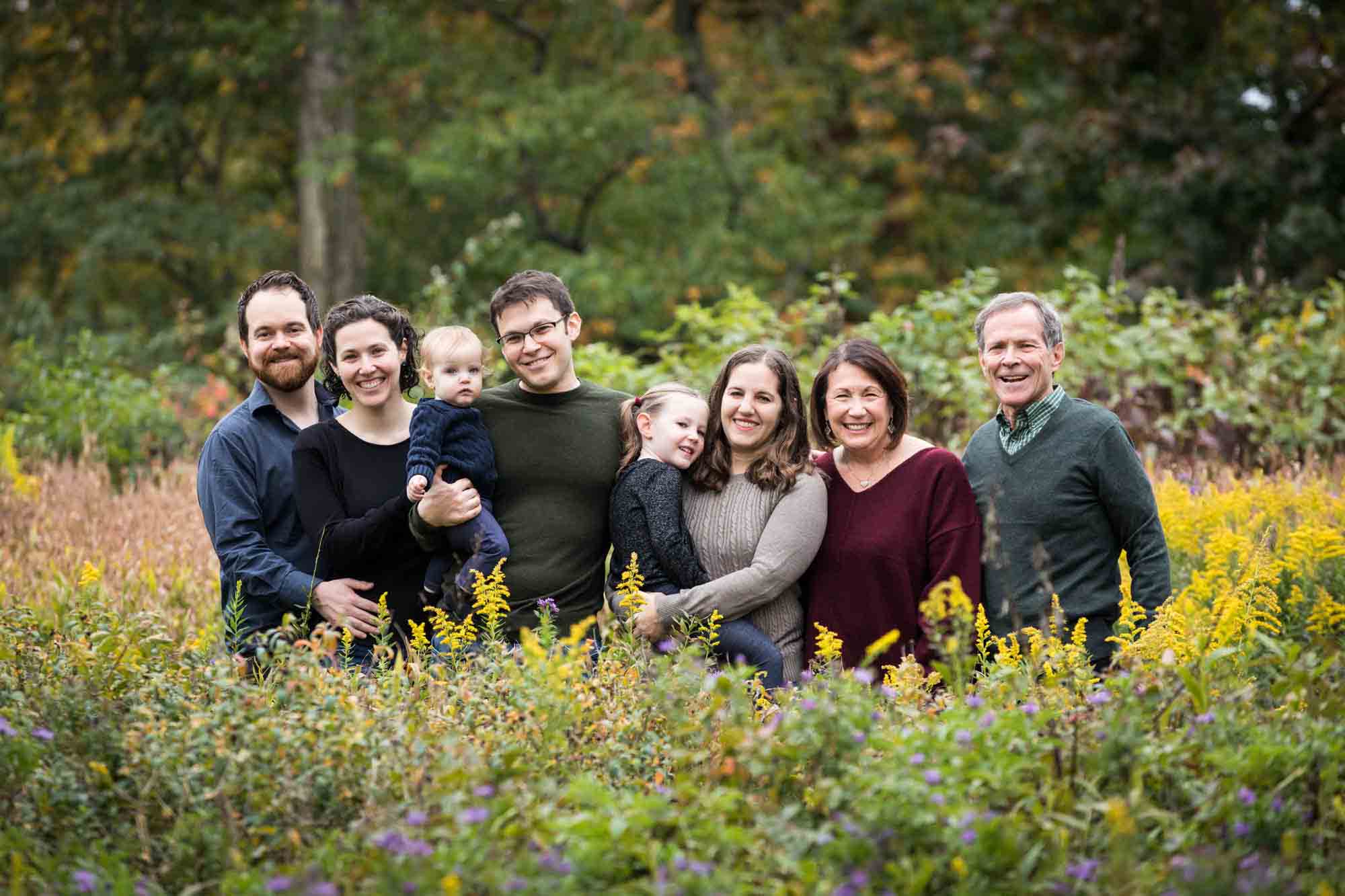 Large family hugging in Forest Park behind bushes