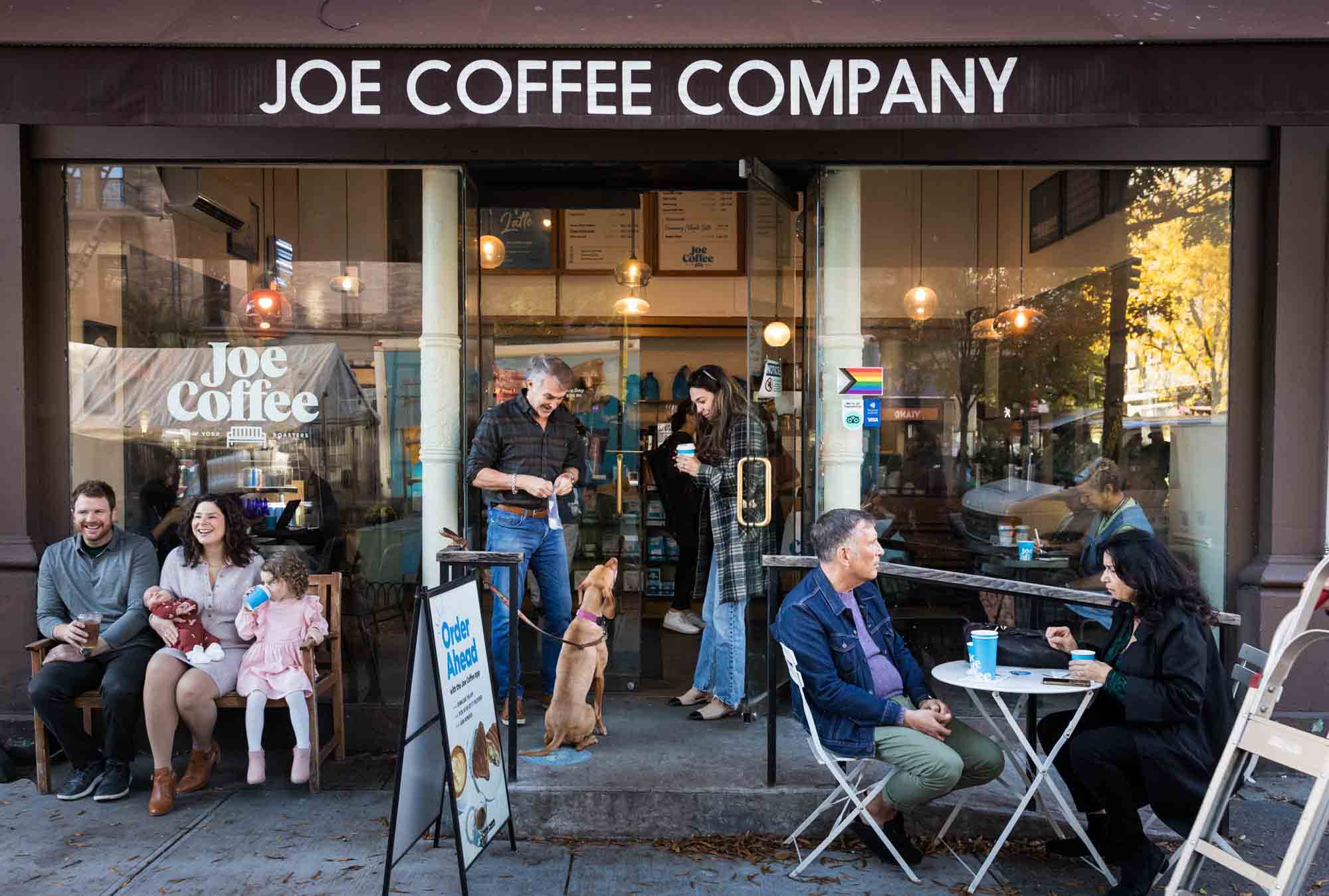 Sidewalk scene of three different families and coup[les in front of Joe Coffee Company in NYC