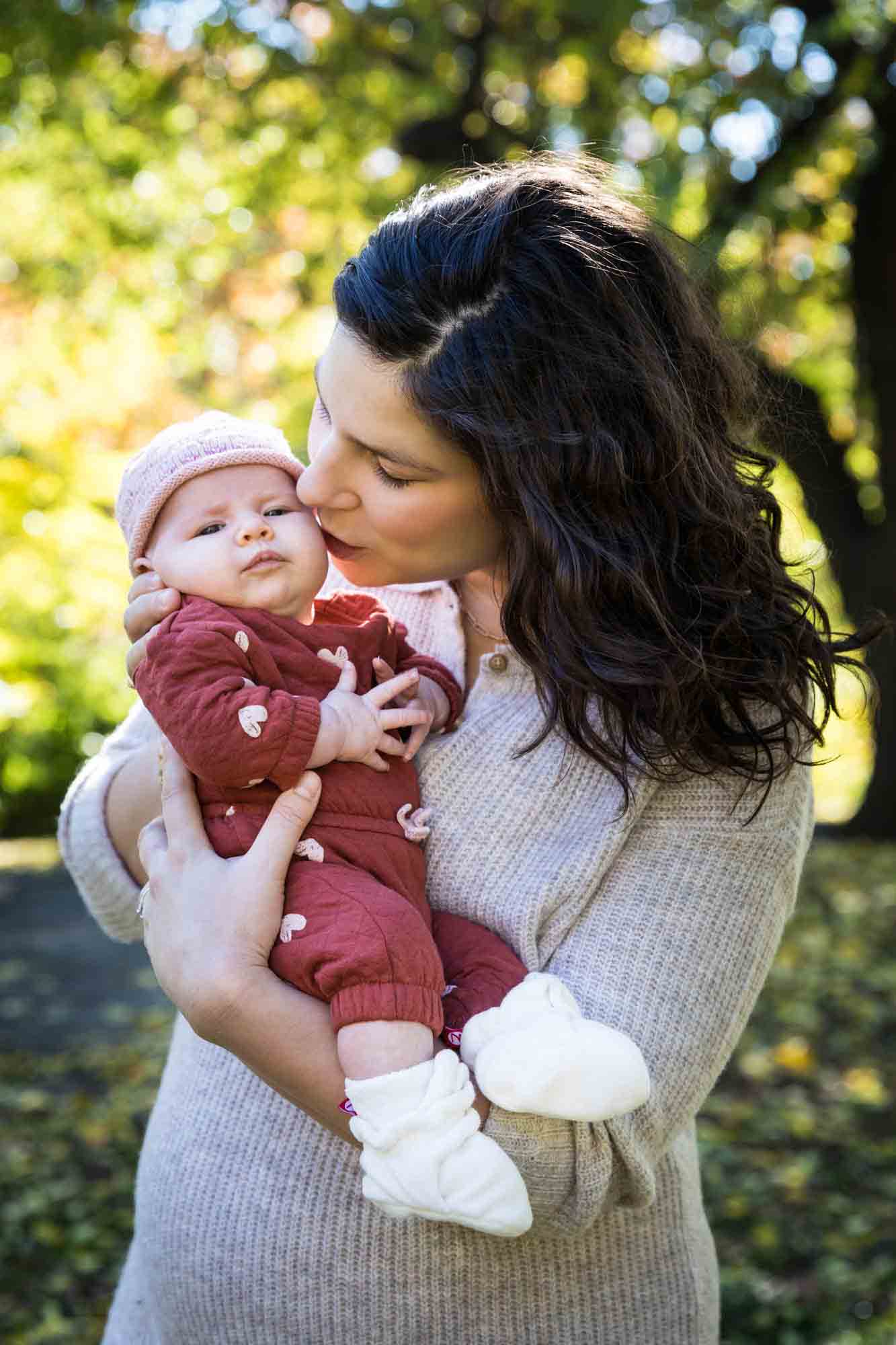 Mother kissing baby wearing red pajamas in Central Park